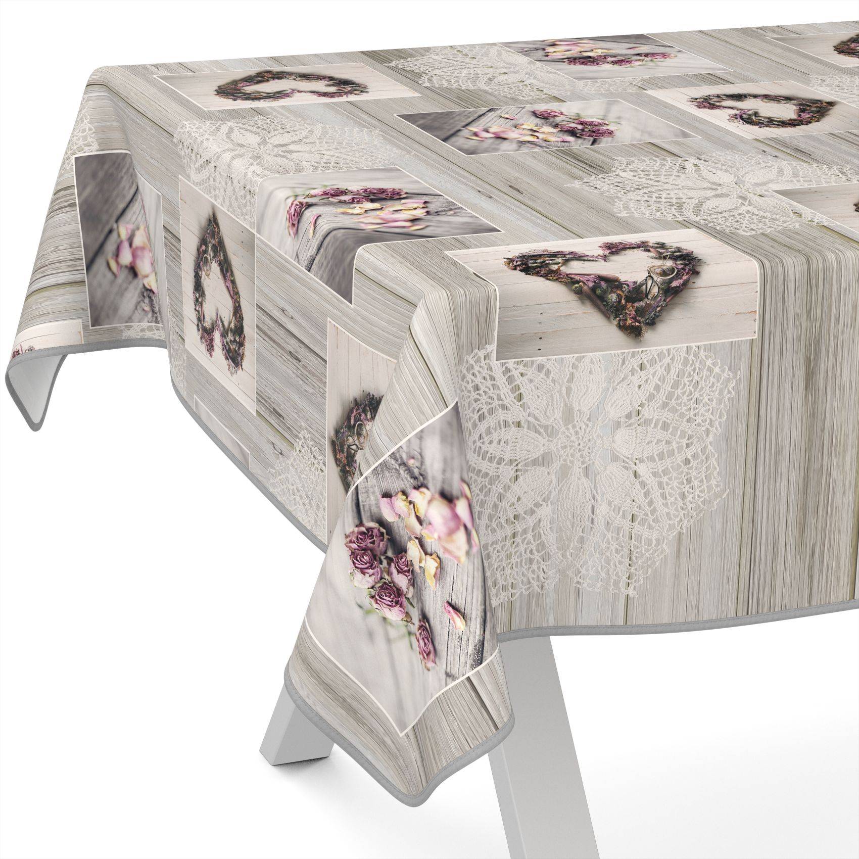 Rechteckiger Tisch mit einer Tischdecke mit Spitzenmuster, das Blumenkränze und Rosendruck in sanften Grau- und Rosatönen zeigt.