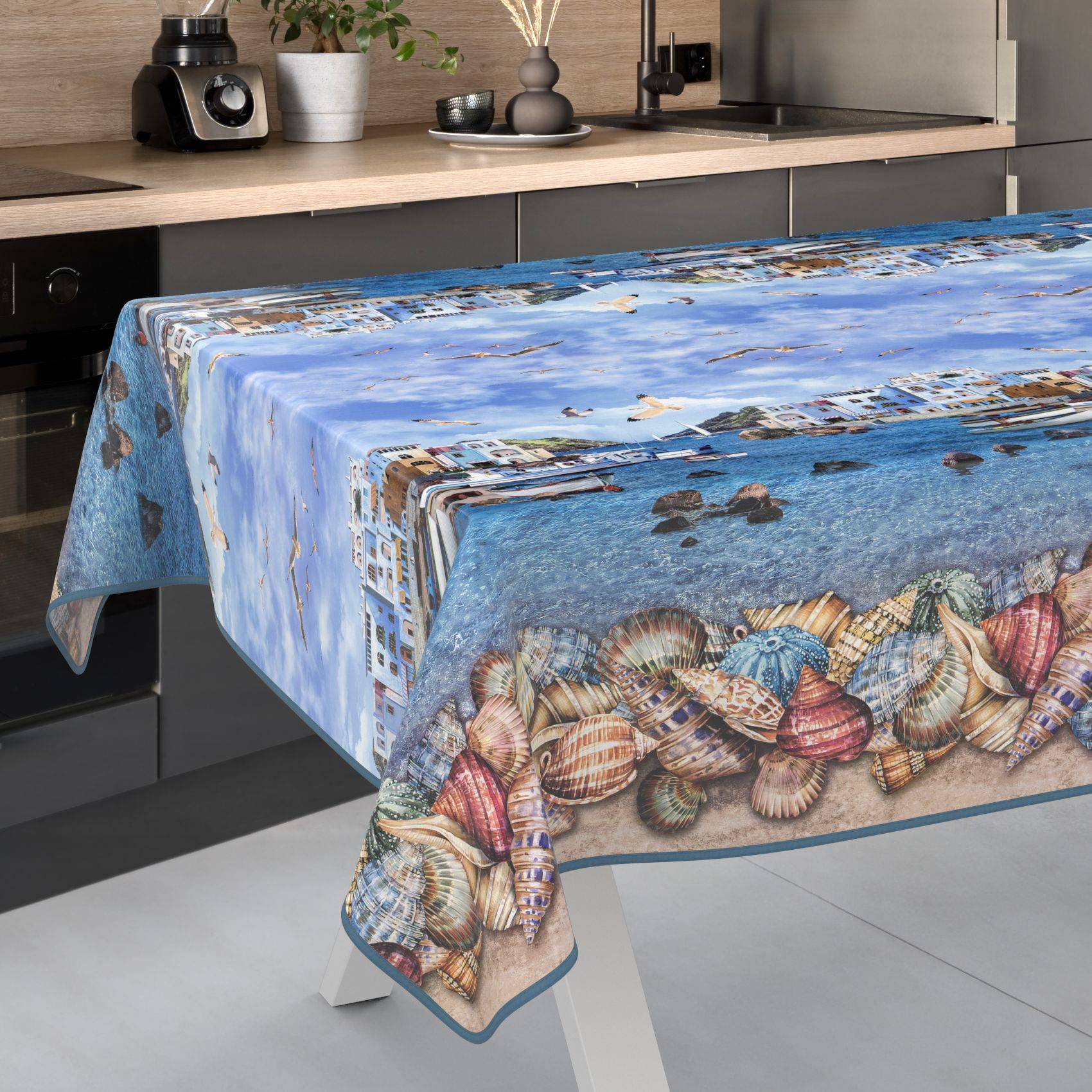 Küchentisch mit einer Tischdecke mit Muschelmuster, die Meerwasser und Muscheln zeigt.
