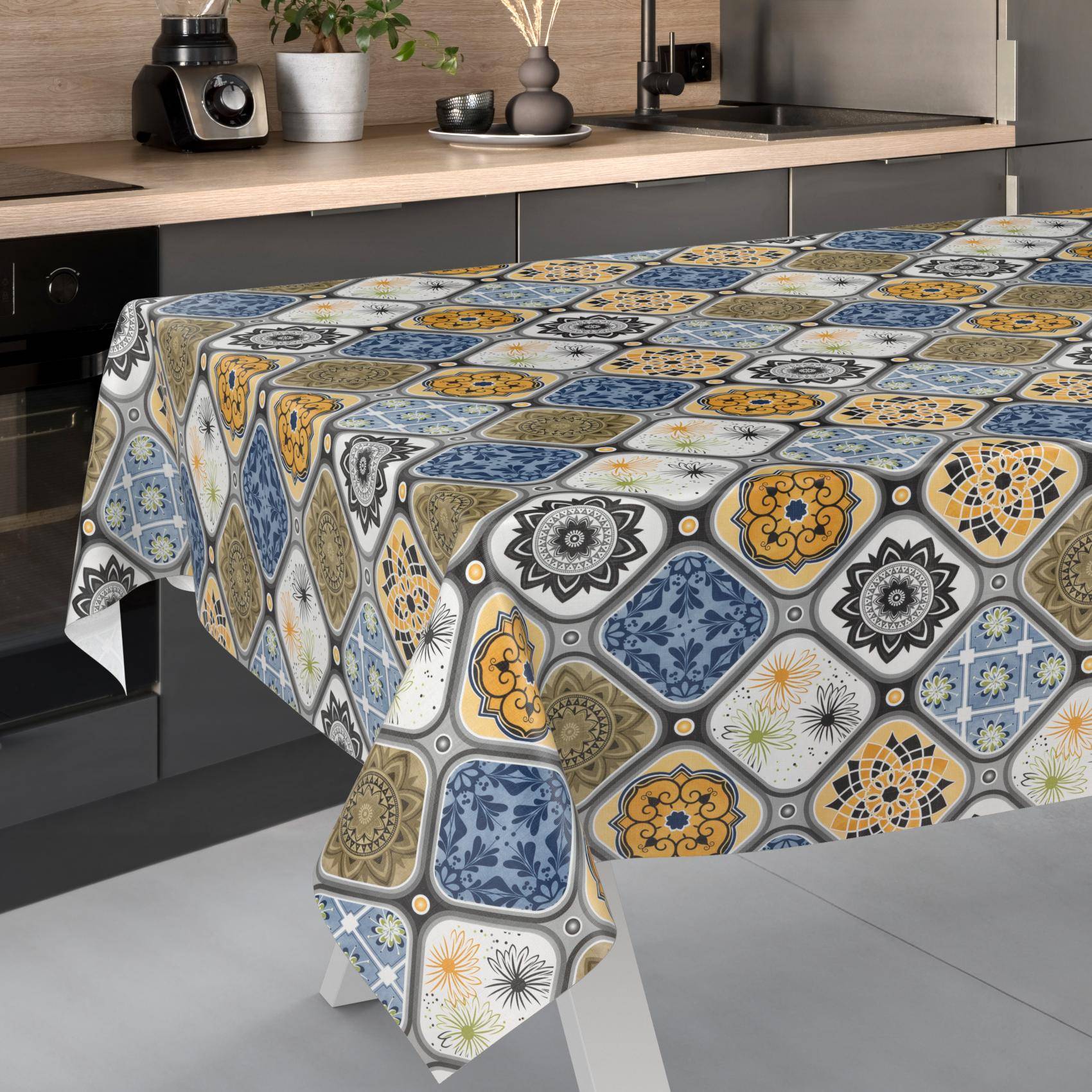 Küchentisch mit einer gemusterten Tischdecke im Mosaik-Stil in Blau, Gelb, Grau und Weiß in einer modernen Küche.