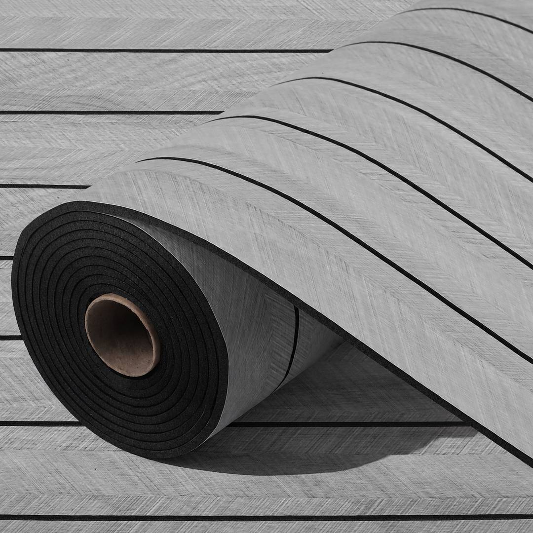 Aufgerollte grau-schwarze Schaumstoff-Bodenmatte mit Holzmaserungsmuster, teilweise ausgerollt auf einer Latten oberfläche gezeigt.