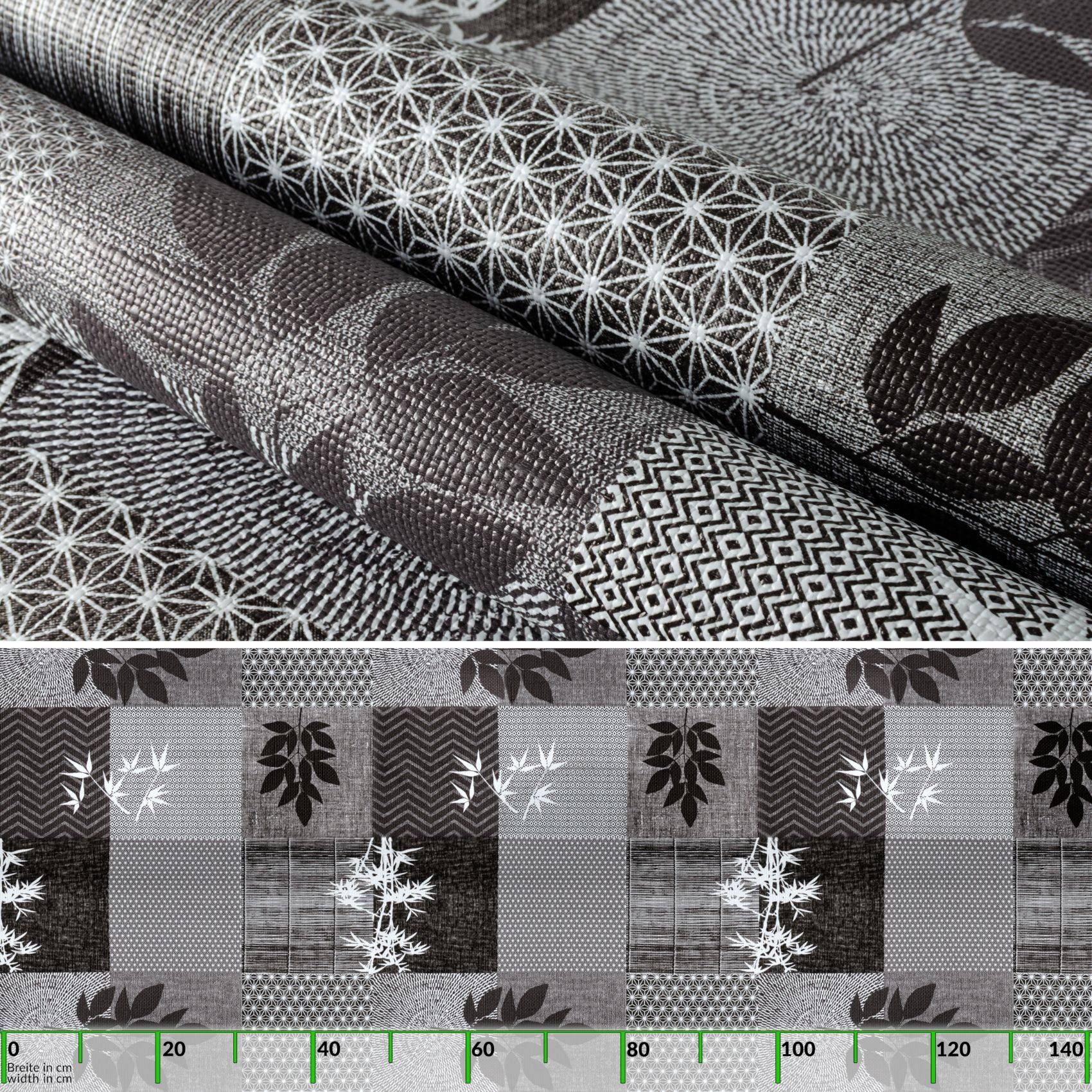 Schwarz-weiß gemusterte Textilmuster mit geometrischen und Blattkortiven, dargestellt als Rollen über einer Patchwork-Stoffprobe mit grüner Messskala am unteren Rand.