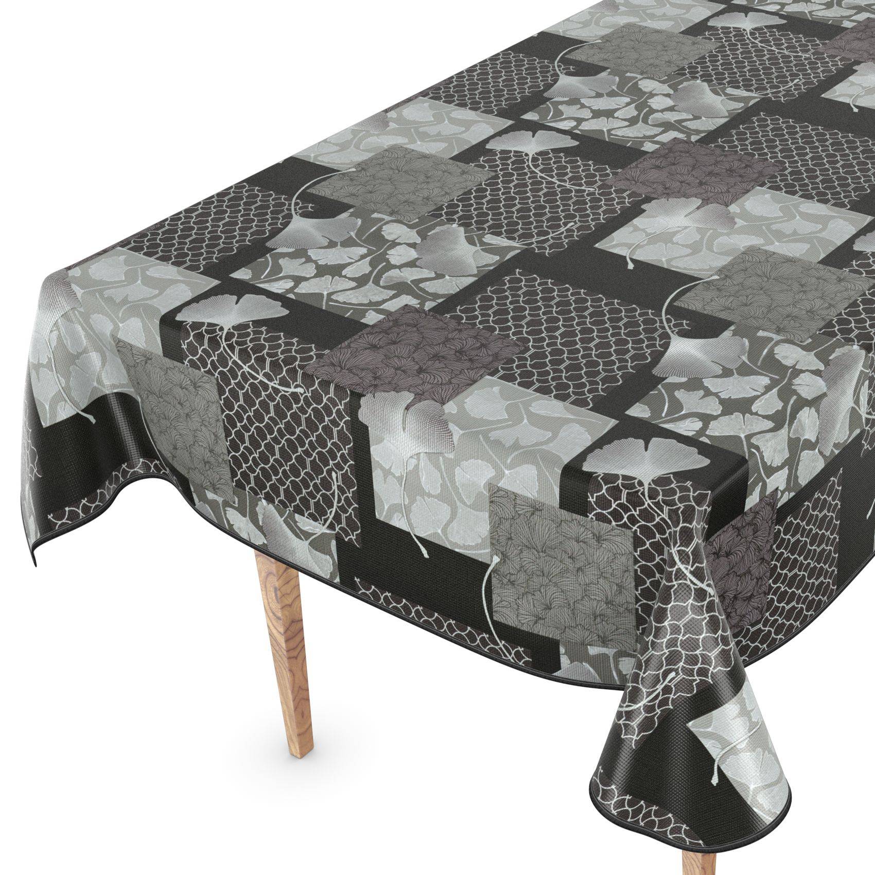 Gemustertes Tischtuch, das über einen Tisch drapiert ist, mit schwarzen, grauen und weißen Patchwork-ähnlichen Quadraten und einem dekorativen Blatt- und Gitterwerk-Design.