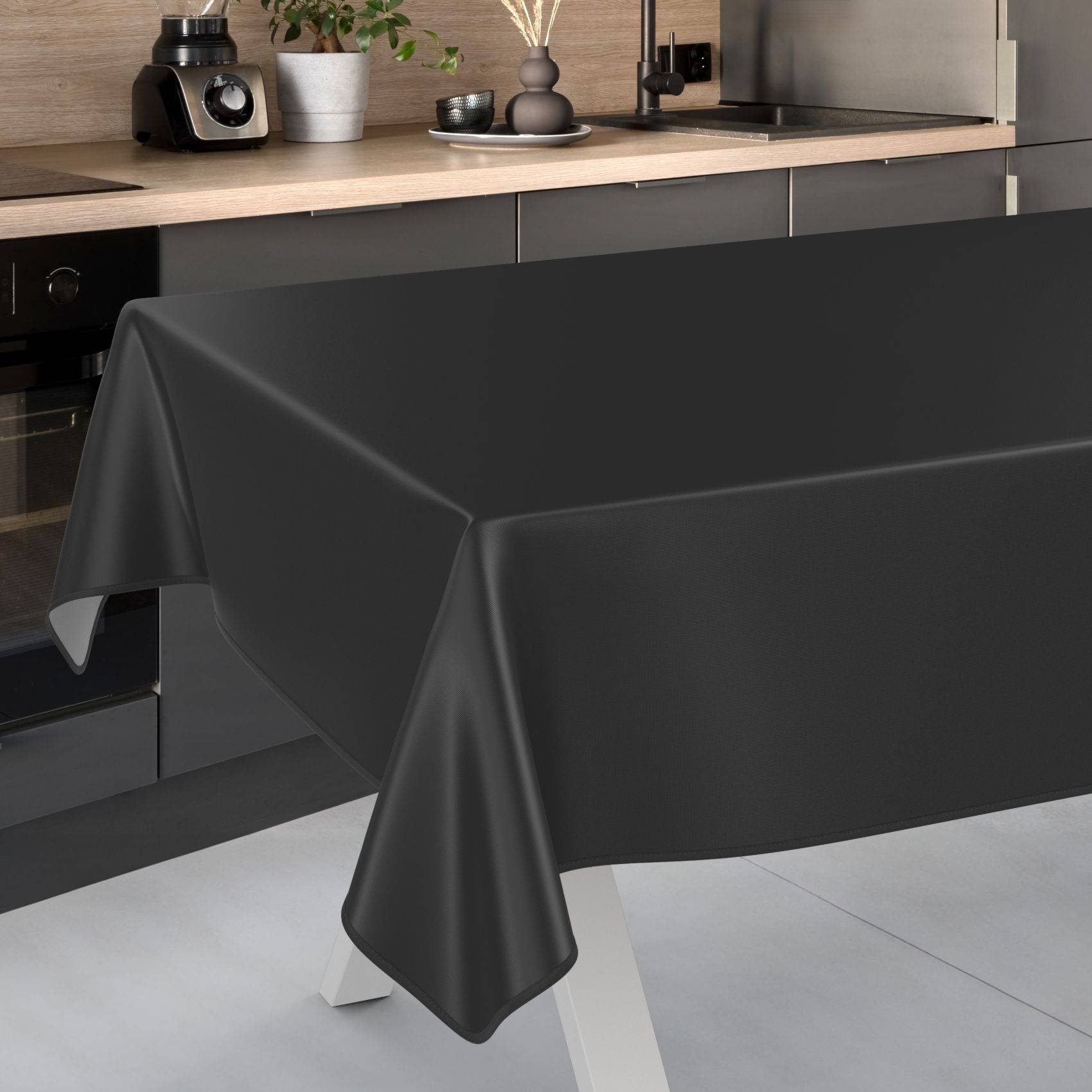Schwarze Tischdecke über einem rechteckigen Tisch in einer modernen Küche drapiert, die den Tisch fast bis zum Boden bedeckt.