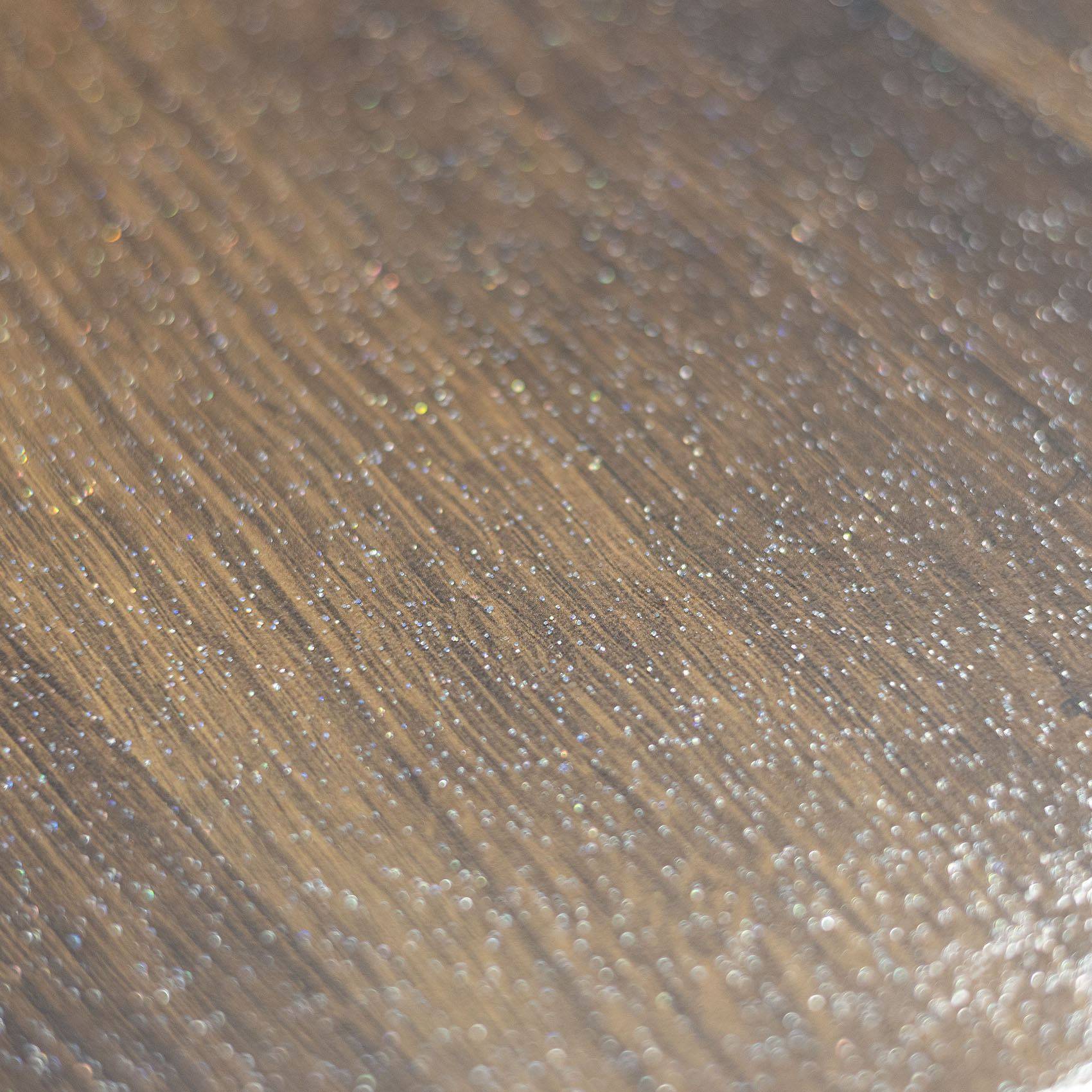 Nahaufnahme einer braunen metallischen oder holzmaserungsstrukturierten Oberfläche mit diagonalen Streifen und Lichtreflexionen.