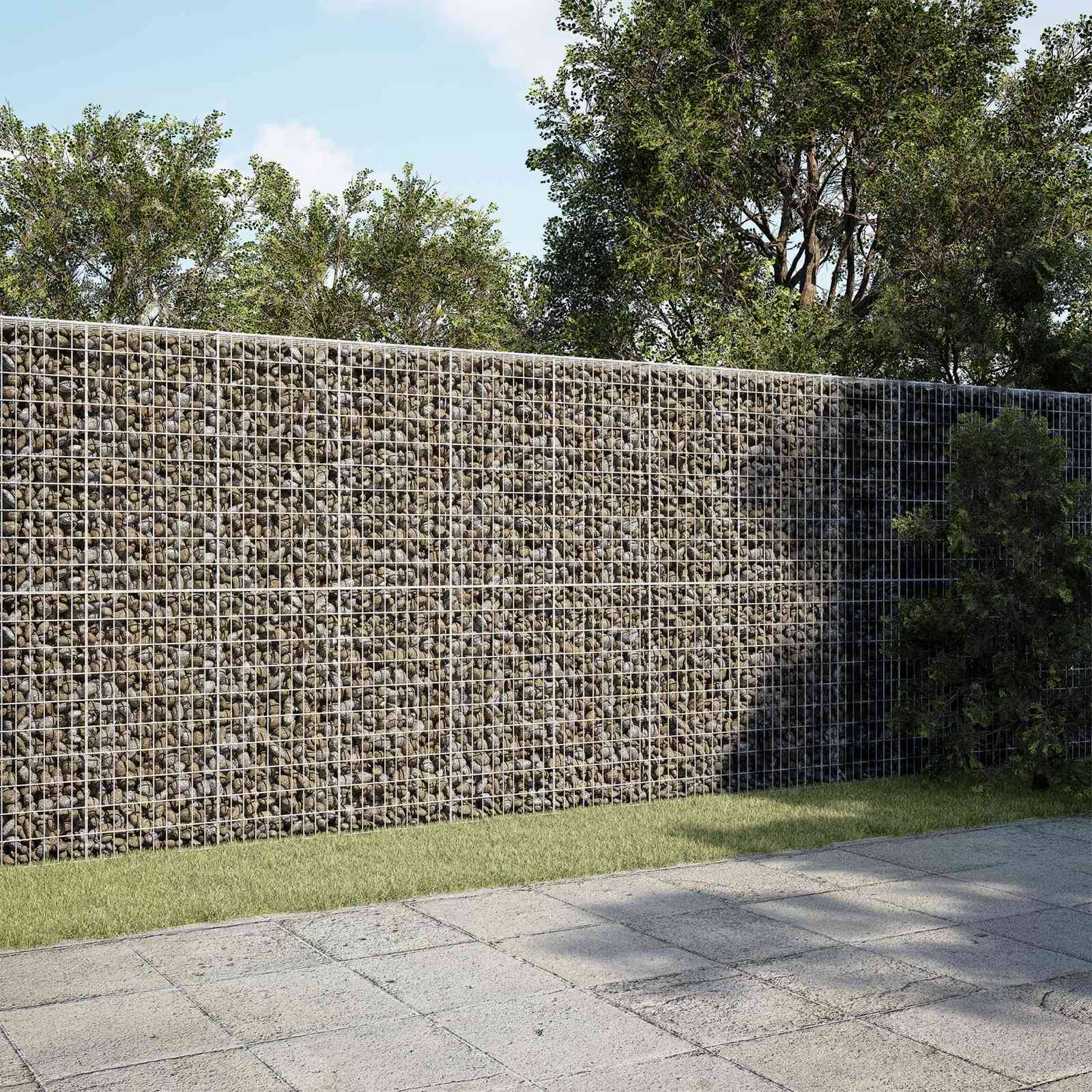 Mit Steinen gefüllte Drahtgitterstützwand neben einem gepflasterten Gehweg, mit Bäumen und Gras im Hintergrund.