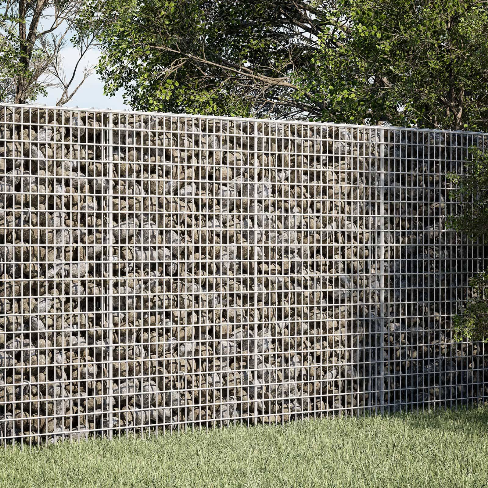 Eine mit Steinen gefüllte Gabionenwand steht hinter einem grasbewachsenen Vordergrund, mit Bäumen darüber.
