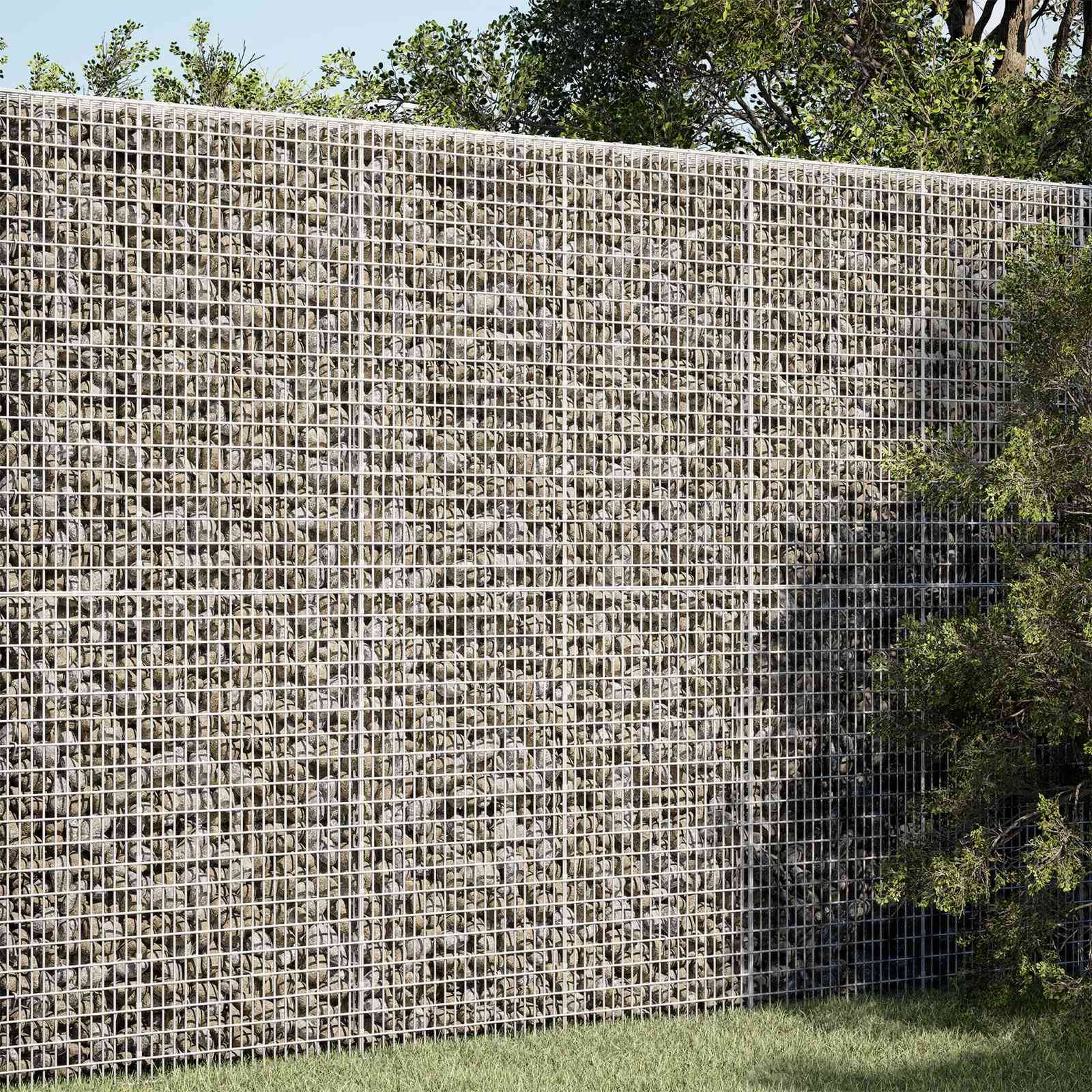 Mit Steinen gefüllte Drahtgitterstützwand neben Gras und Bäumen, die eine hohe strukturierte Barriere im Freien bildet.