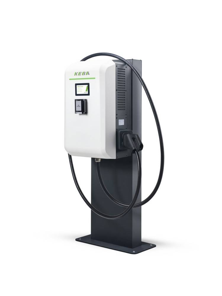 Weiße und schwarze Ladestation für Elektrofahrzeuge mit Bildschirm, Stecker und aufgerolltem Kabel auf einem Bodenständer.