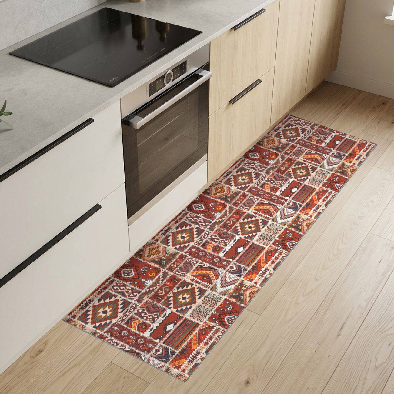 Moderne Küche mit eingebautem Ofen und Kochfeld neben einem langen gemusterten Läuferteppich auf einem Holzboden in heller Farbe.