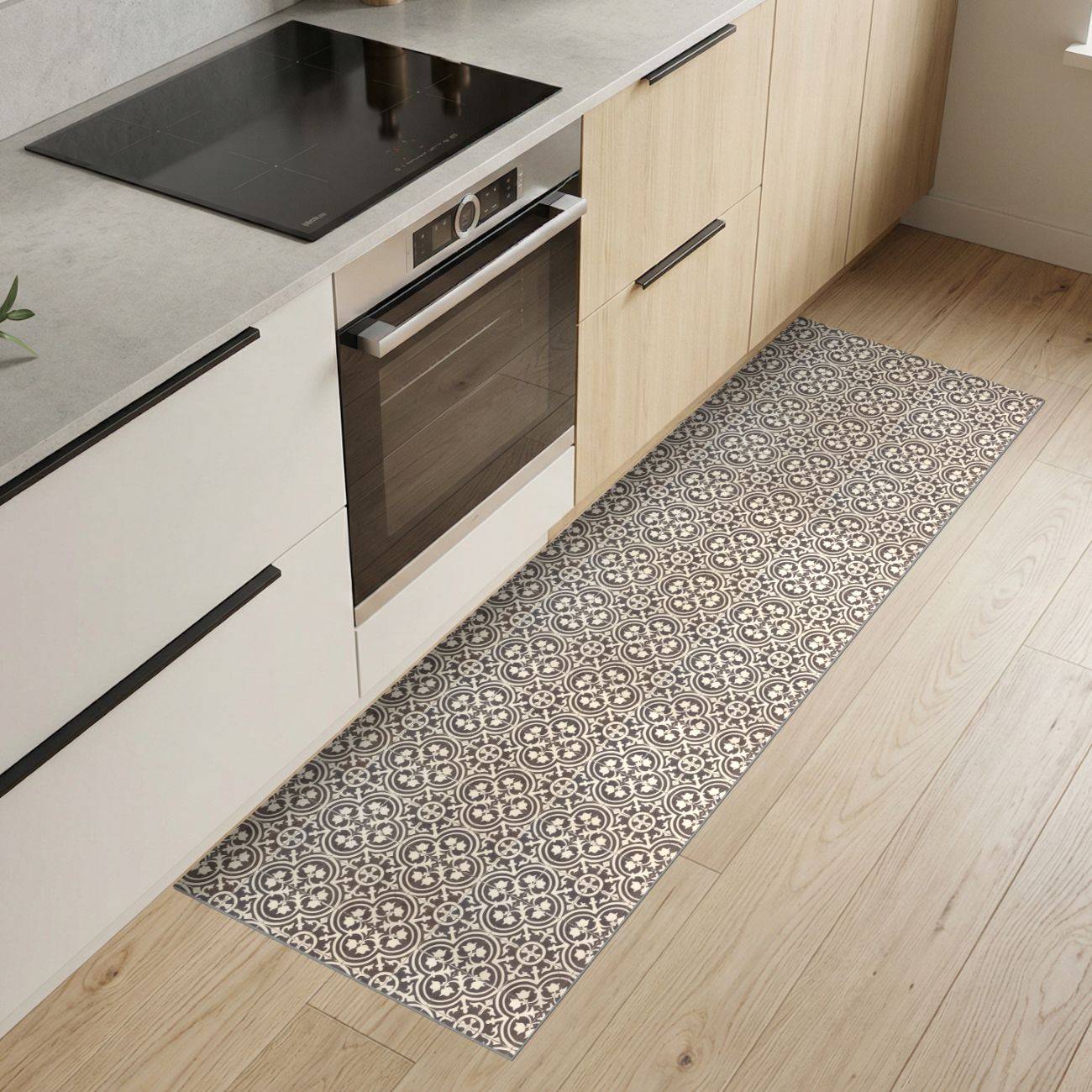 Moderne Küche mit hellem Holzschrank, eingebautem Ofen und schwarzem Kochfeld sowie einem gemusterten Läuferteppich auf dem Boden.