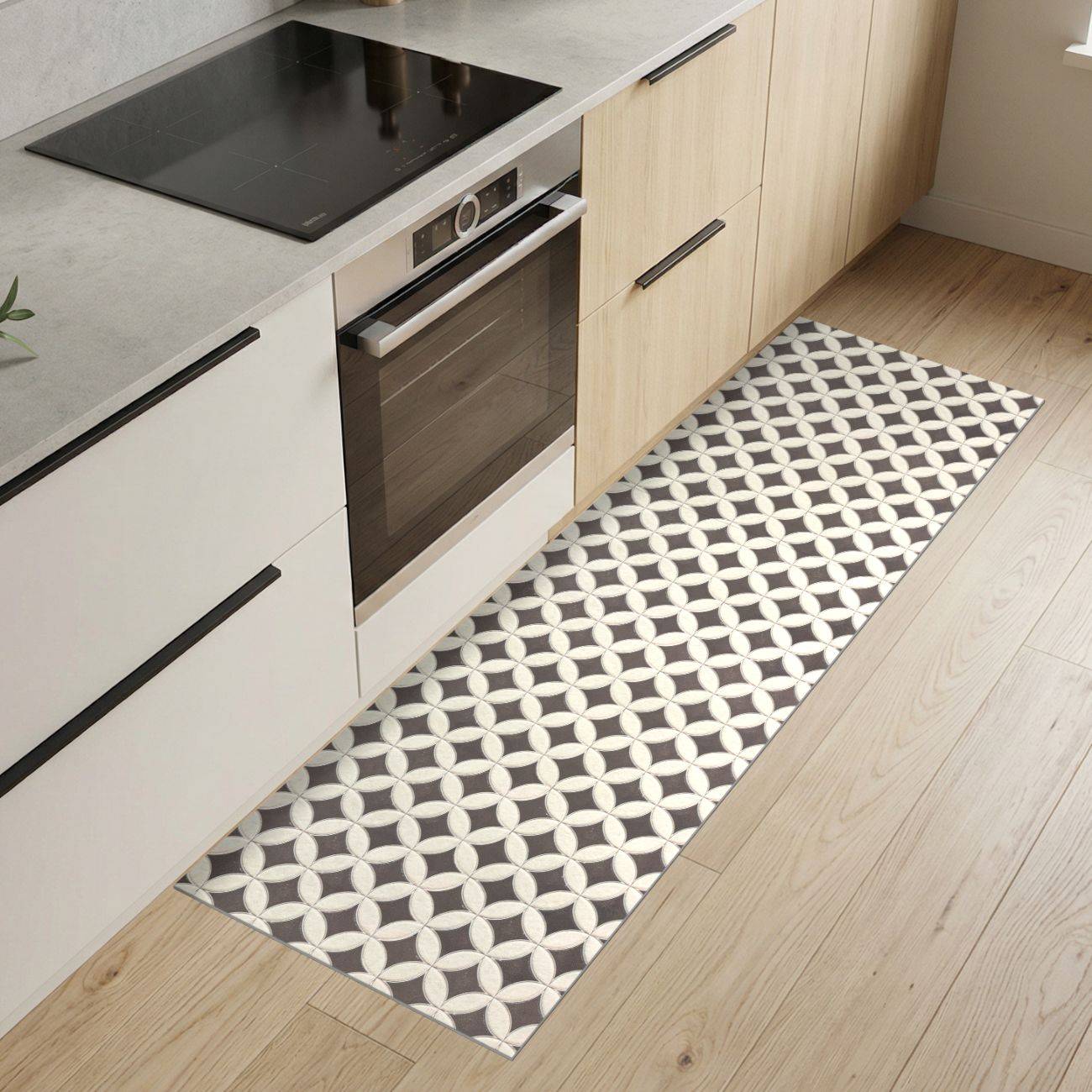 Moderne Küche mit hellen Holzschränken, eingebautem Ofen, schwarzem Kochfeld und einem gemusterten Läufer auf dem Boden.
