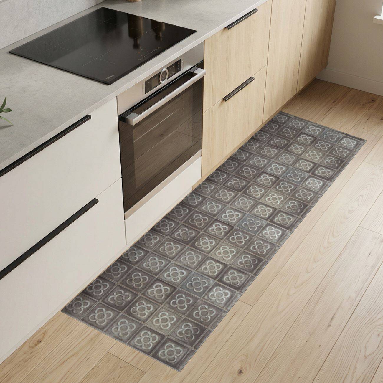 Moderne Küche mit hellen Holzschränken und weißen Schränken, eingebautem Ofen, schwarzem Kochfeld und einem gemusterten grauen Läuferteppich auf dem Boden.