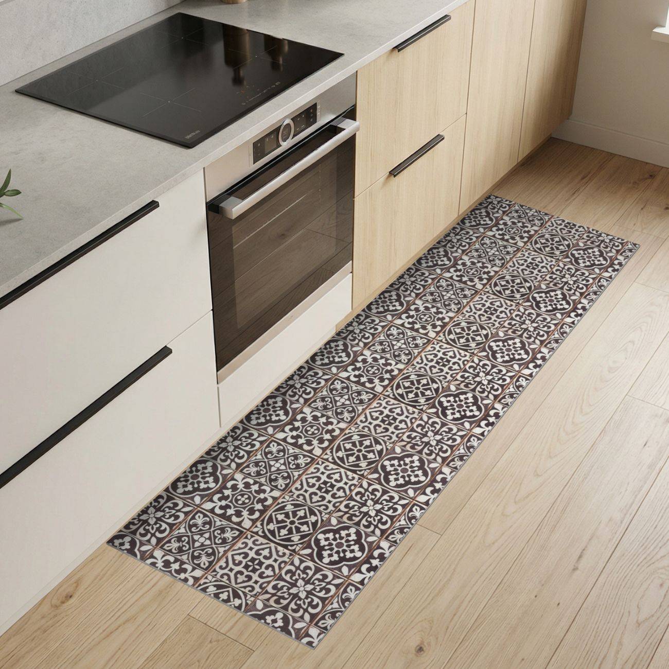 Moderne Küche mit hellen Holzschränken, eingebautem Backofen, schwarzem Kochfeld und einem gemusterten Läufer auf dem Boden.