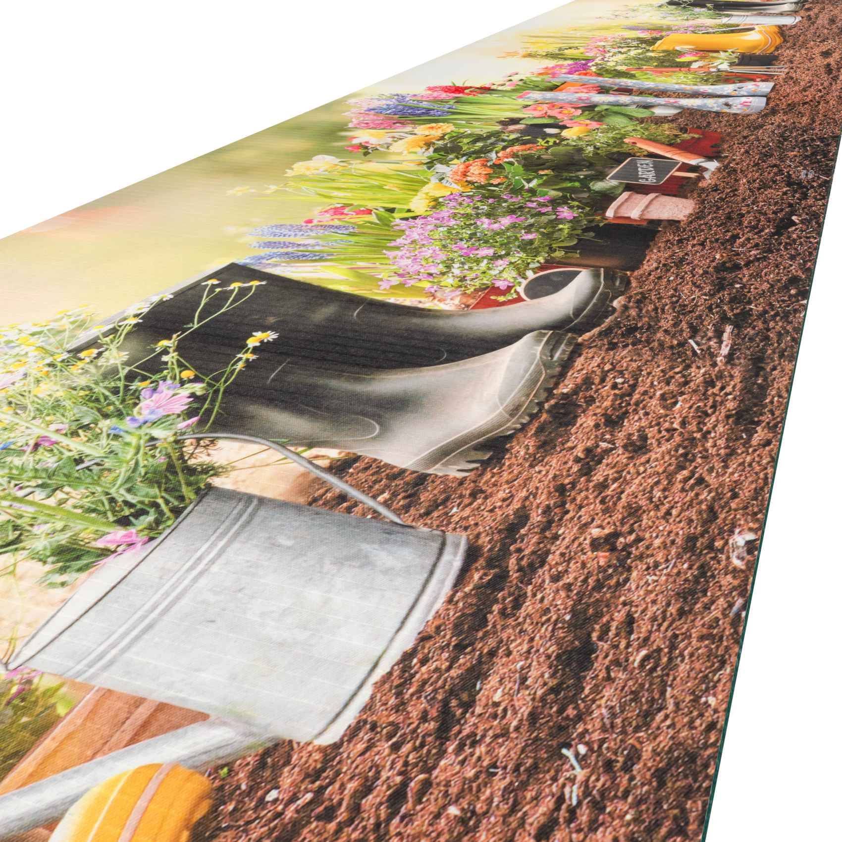 Mehrere Gartenspaten und Handwerkzeuge liegen in der Erde neben farbenfrohen Blumen in einem Blumenbeet, was auf Gartenarbeit oder Landschaftsgestaltung hindeutet.