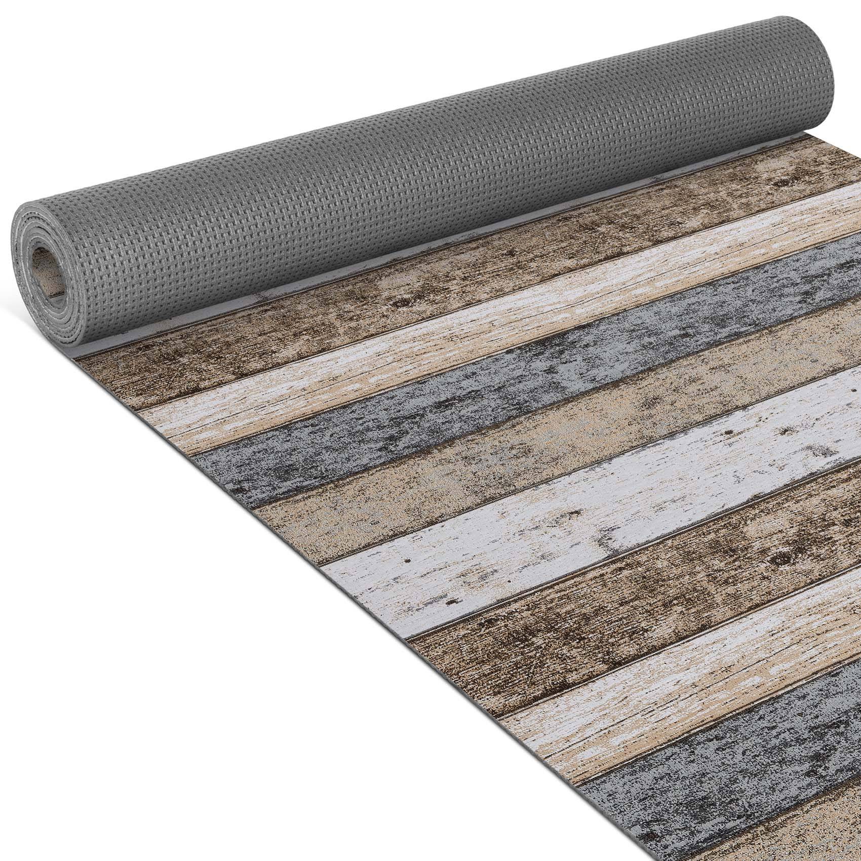 Aufgerollter grauer Flächenteppich mit verwittertem Holzdielen-Druck in Tan, Weiß und Grau.