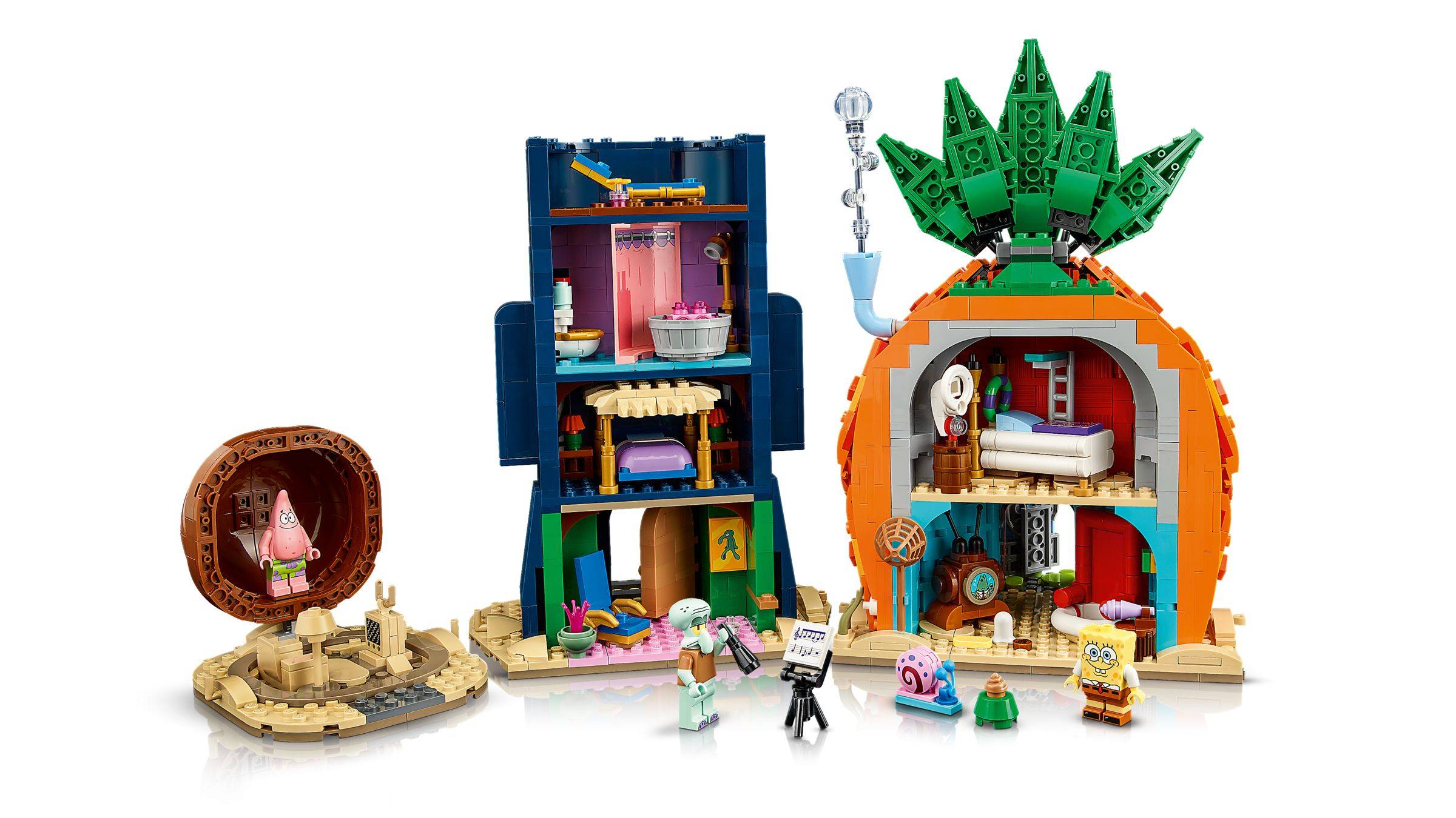 LEGO SpongeBob Spielset mit dem Ananashaus, SpongeBobs Hausinneres, einem hohen blauen Gebäude und einem kleinen runden sandigen Bauwerk mit Minifiguren im Vordergrund.