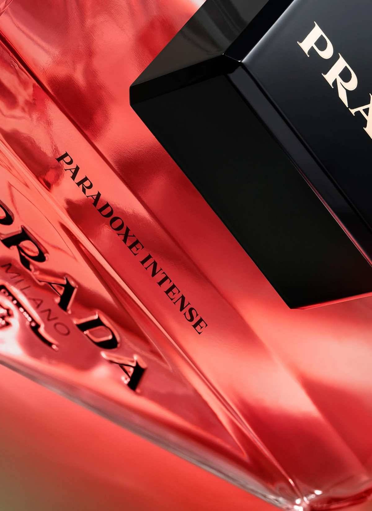Nahaufnahme einer roten Prada-Parfümflasche mit der Aufschrift „PRADA" und „PARADOXE INTENSE"" mit schwarzem Verschluss.