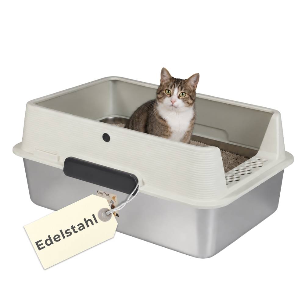 Tabby-Katze, die in einer abgedeckten Katzentoilette mit einem Schaufelgriff sitzt, und ein hängendes Etikett mit der Aufschrift „Edelstahl