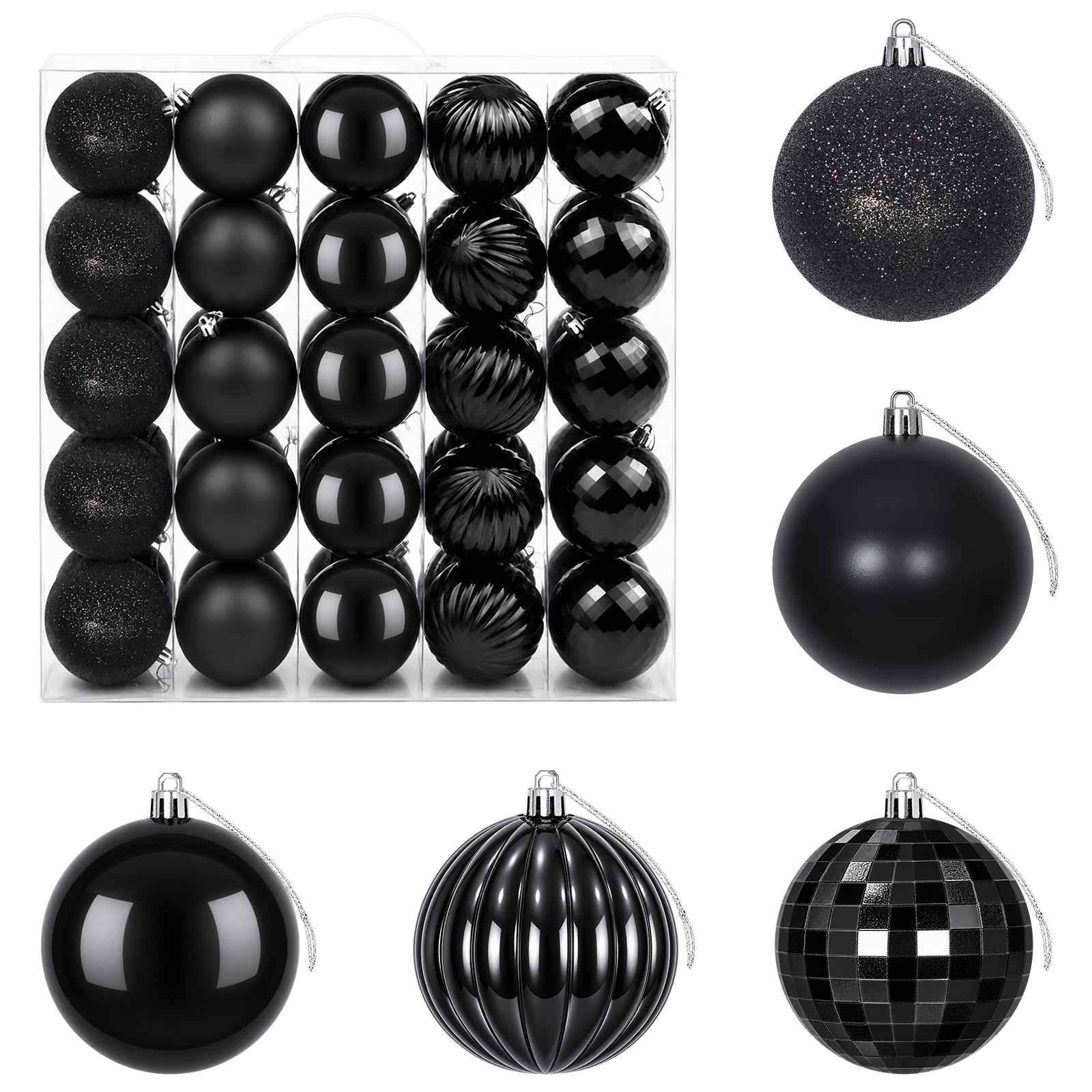 Assortierte schwarze Weihnachtskugeln in einem Tablett und als einzelne Kugeln gezeigt, mit matter, glänzender, glitternder, gerippter und karierter Oberfläche.