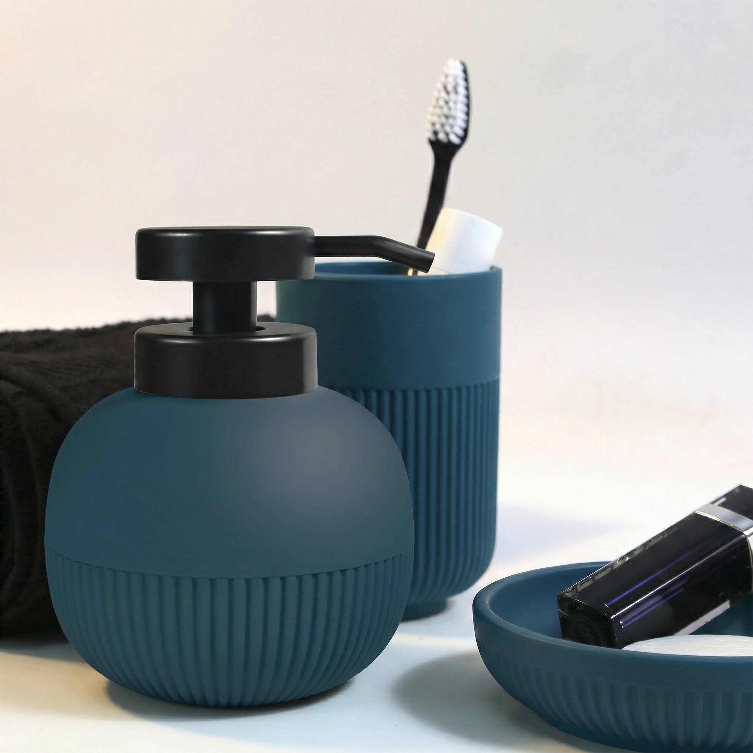 Blaues Badezimmeraccessoires-Set mit Seifenspender, Zahnbürstenhalter und Tablett mit dunkler Zahnbürste und Toilettenflaschenartikel.