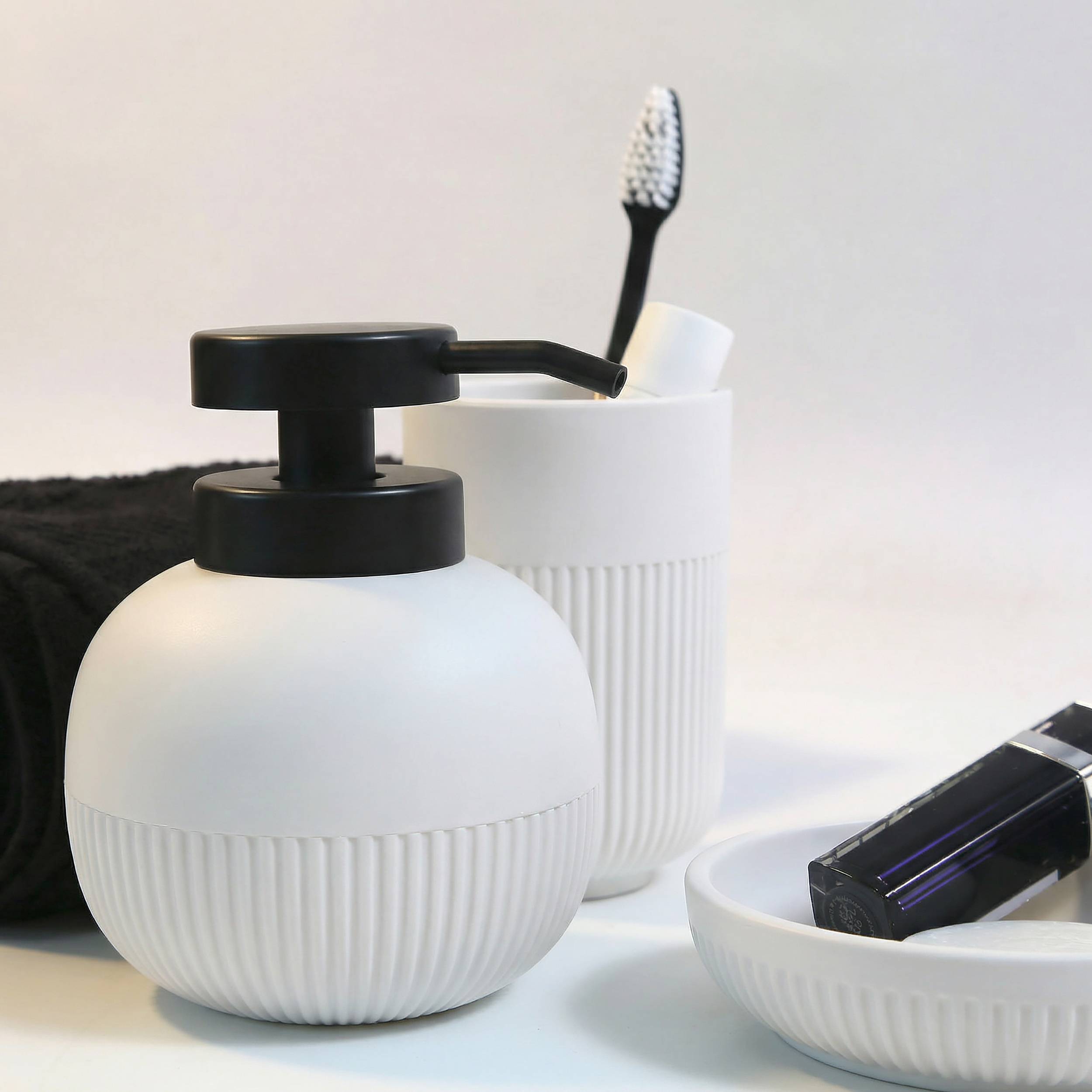 Badezimmer-Ablageset mit weißem gerilltem Seifenspender, Zahnbürstenhalter und Schale mit schwarzer elektrischer Zahnbürste oder Rasierer.