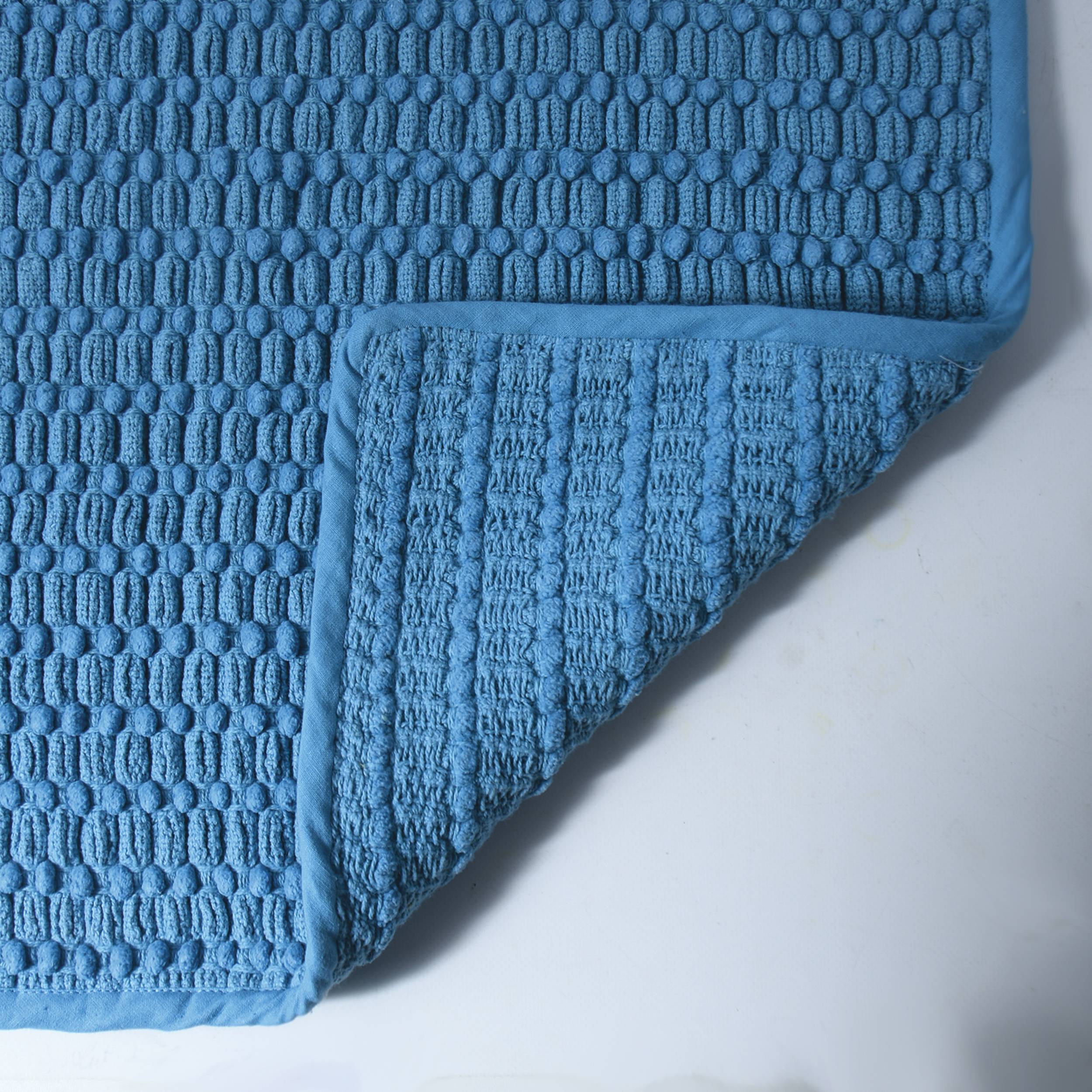 Blaue strukturierte gefaltete Decke oder Handtuch mit einem waffelartigen Muster auf hellem Hintergrund.