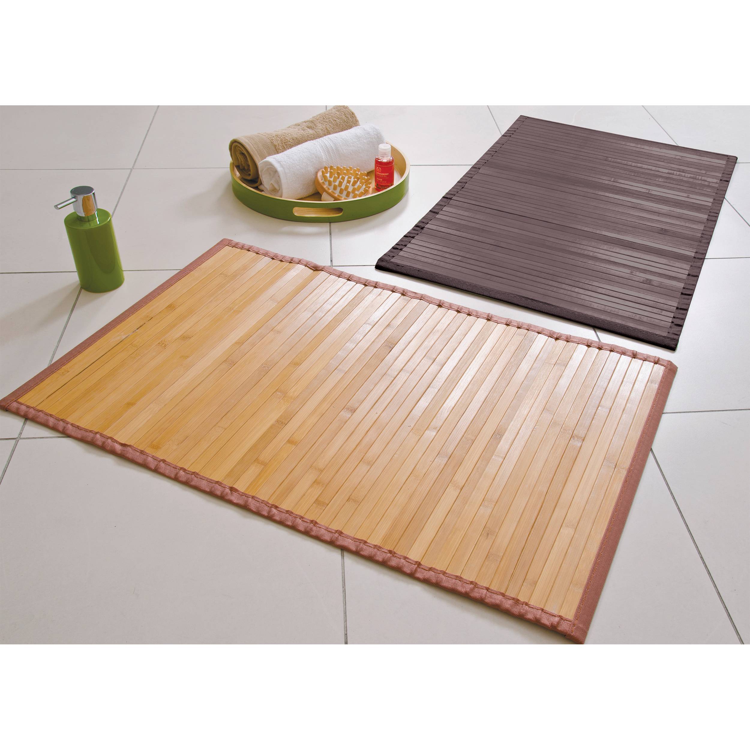 Drei gerollte Bambusfloormatten in verschiedenen Farben und ein kleines Tablett mit Spa-Artikeln auf einem gefliesten Boden.