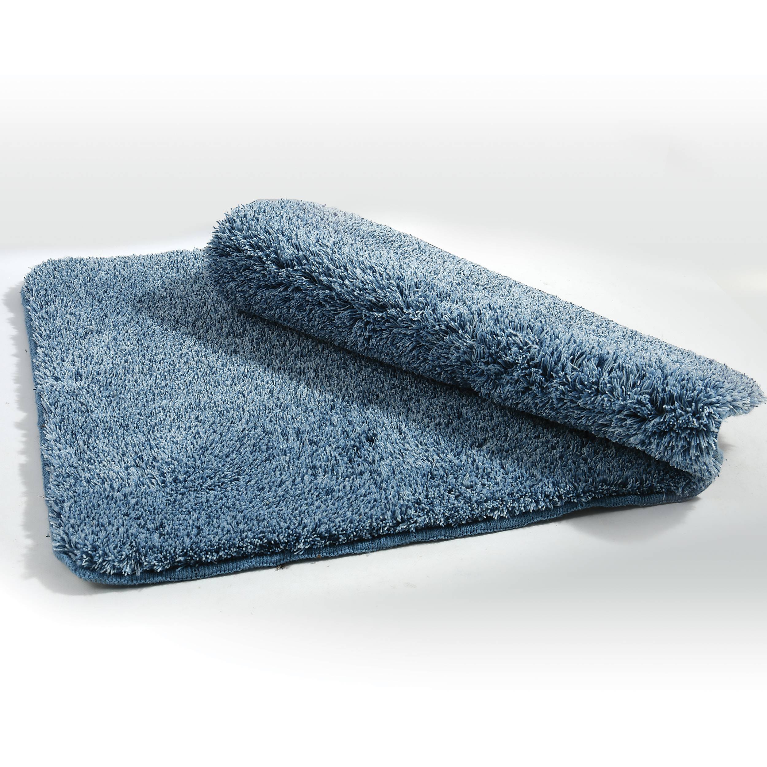 Blauer flauschiger Badezimmerteppich, auf weißem Hintergrund gefaltet, zeigt dicke, plüschige Textur und rechteckige Form.