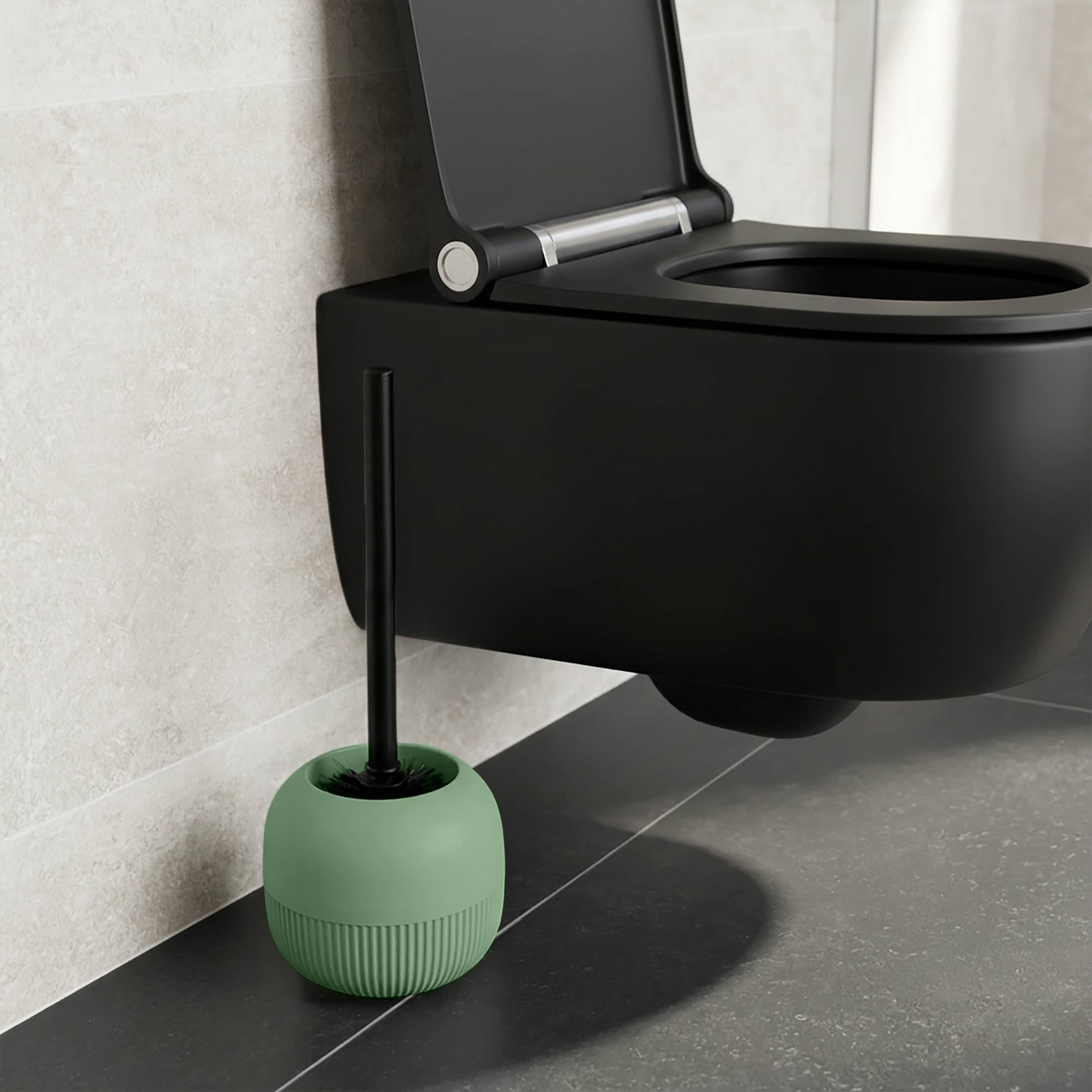 Eine mattschwarz wandmontierte Toilette mit offener Brille und eine grüne Toilettenbürste in ihrem Halter auf einem gefliesten Badezimmerboden.