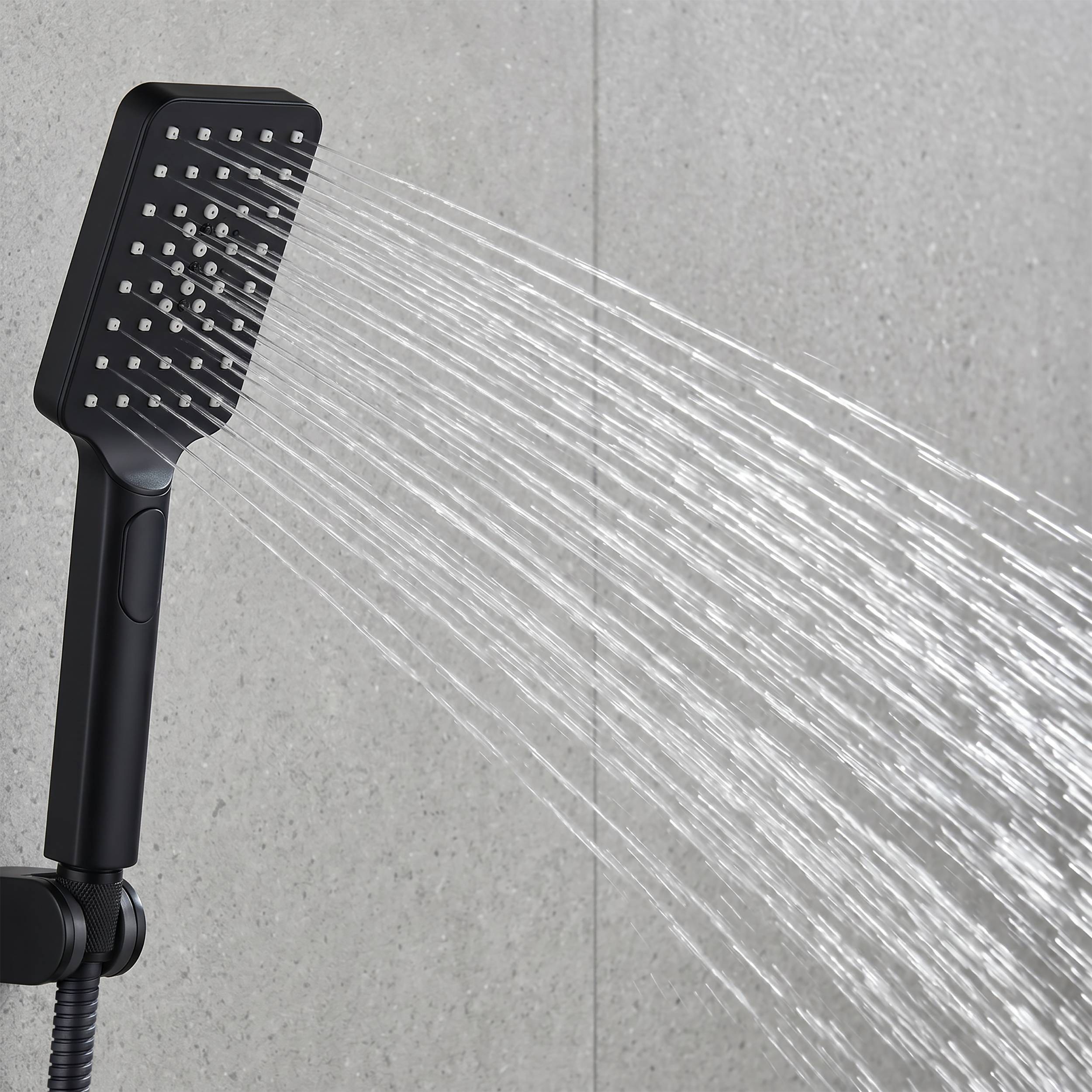 Schwarzer tragbarer Duschkopf, der mehrere Wasserstrahlen gegen eine graue geflieste Badezimmerwand sprüht.
