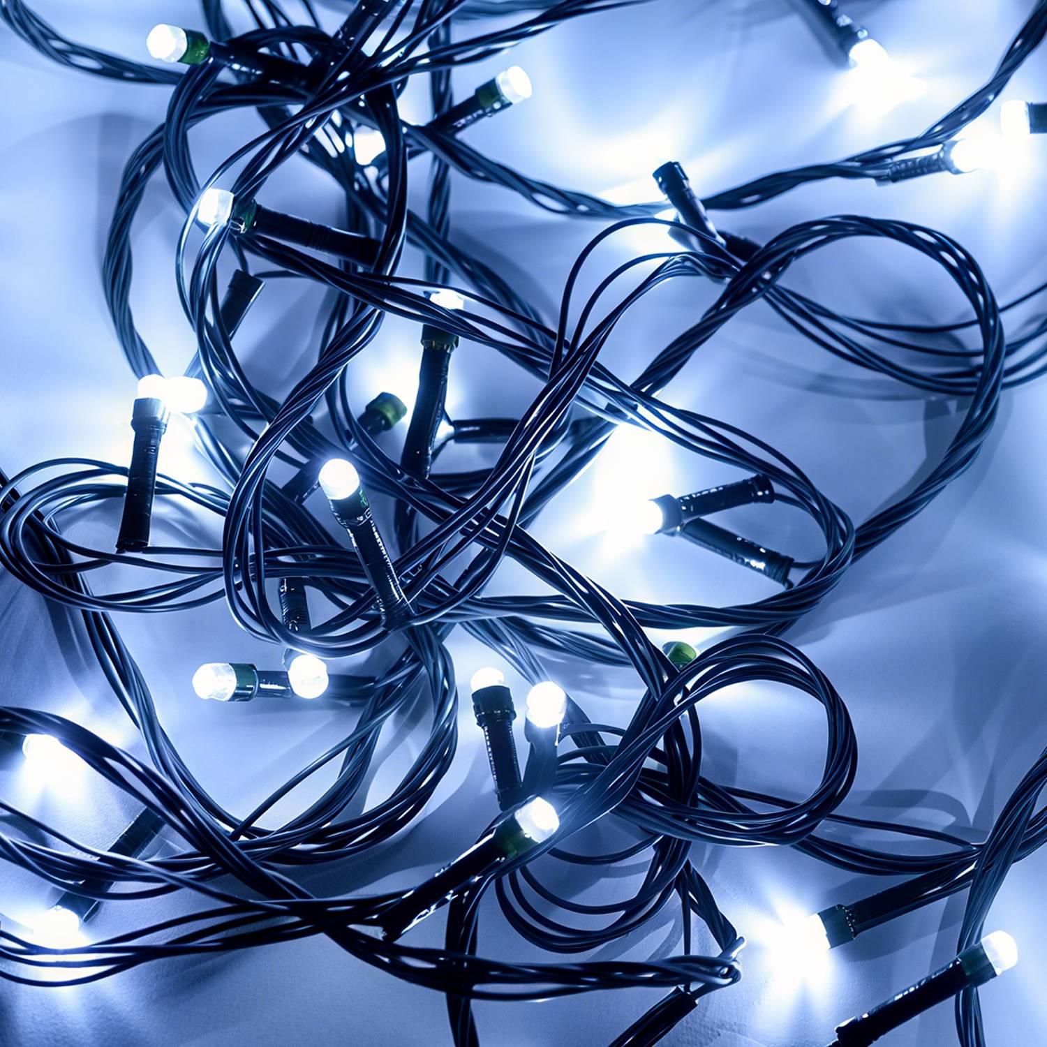 Verworrene schwarze Lichterketten mit kleinen leuchtenden weißen Glühbirnen auf einer hellen Oberfläche, die eine helle dekorative Lichtdisplay erzeugen.