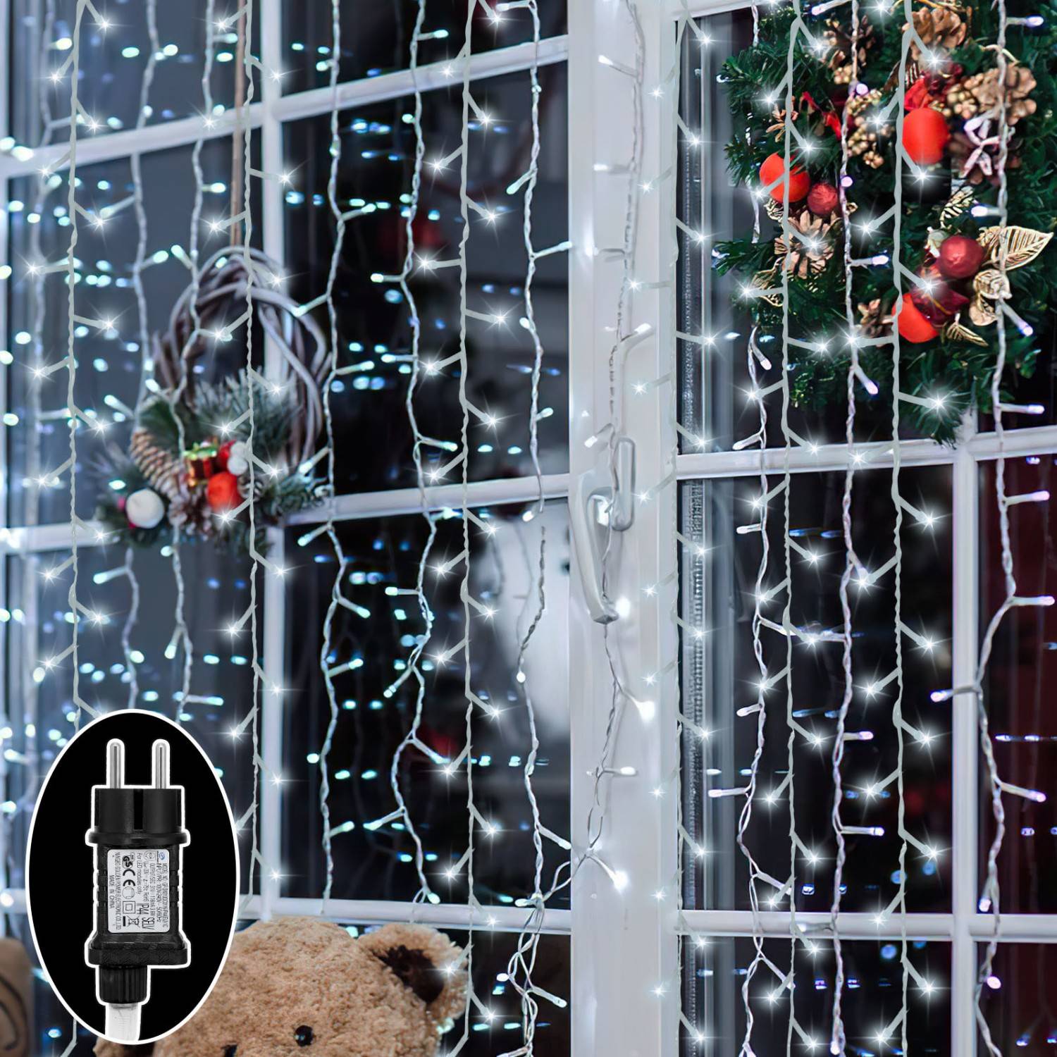 Fenster dekoriert mit hängenden weißen Weihnachtslichtern und Weihnachtskränzen, mit einem schwarzen outdoor Stromadapter unten links.