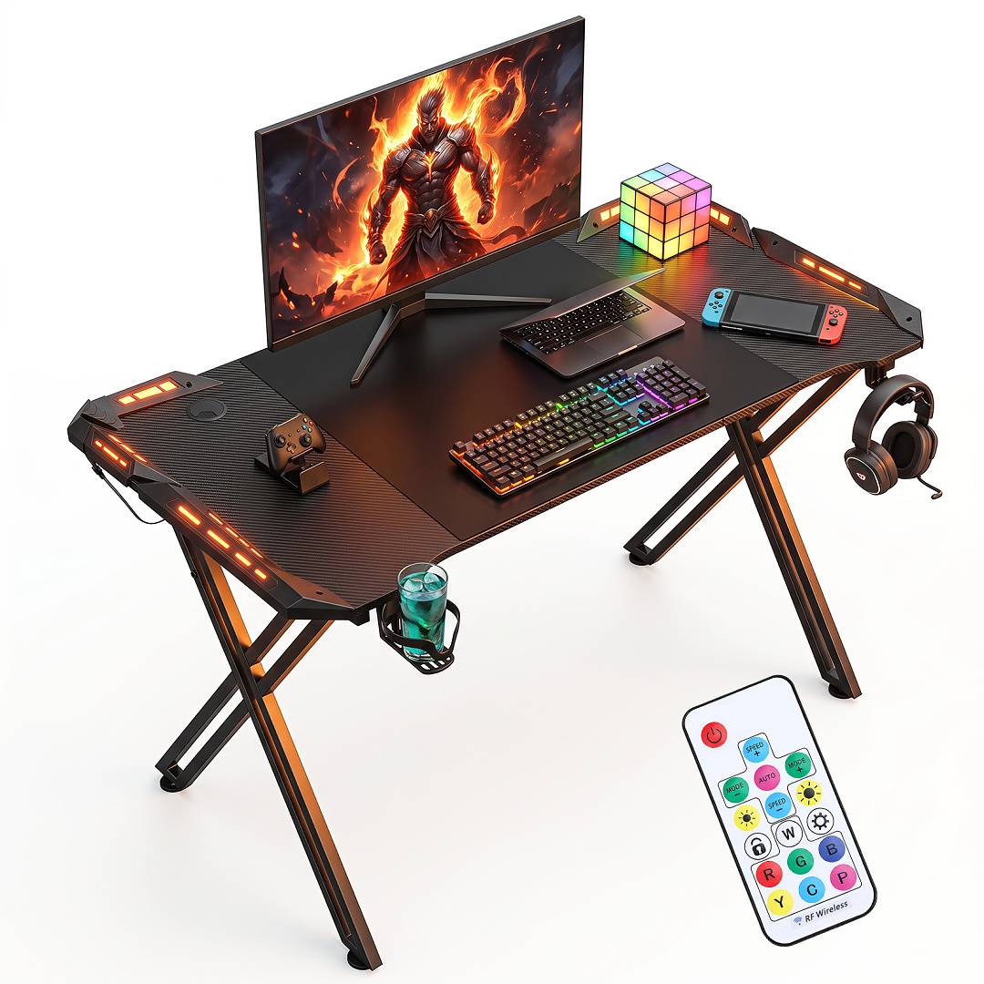 Gaming-Schreibtisch-Setup mit Monitor, RGB-Tastatur, Controller, Telefon, Kopfhörer, Becherhalter und Fernbedienung auf einem schwarzen LED-beleuchteten Schreibtisch.