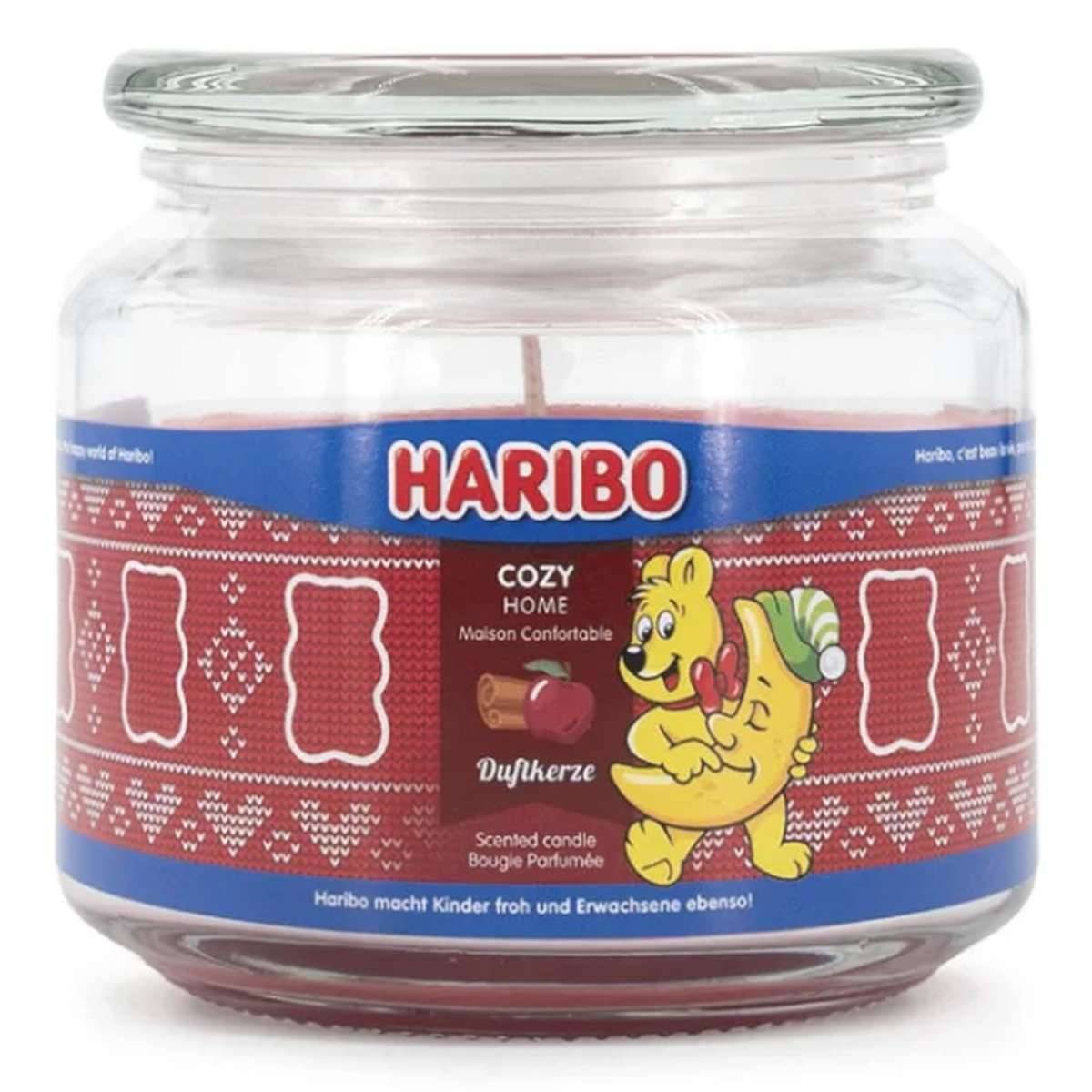 Haribo Cozy Home Duftkerze in einem klaren Glasgefäß mit einem roten gemusterten Etikett und einer Bären- und Gummibärchen-Illustration.