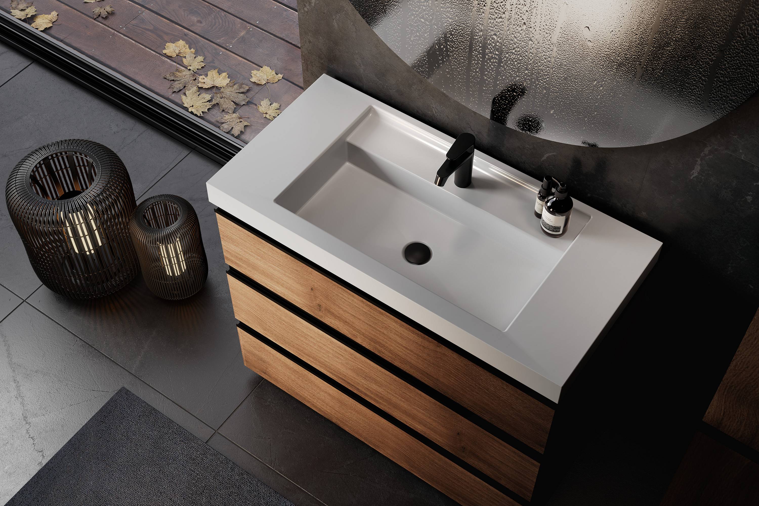 Modernes Badezimmervandou mit Holzschubladen, rechteckigem weißem Waschbecken, schwarzem Wasserhahn und Seifenspender, neben einem mattierten runden Spiegel und geflochtenen Körben auf dunklem Fliesenboden.