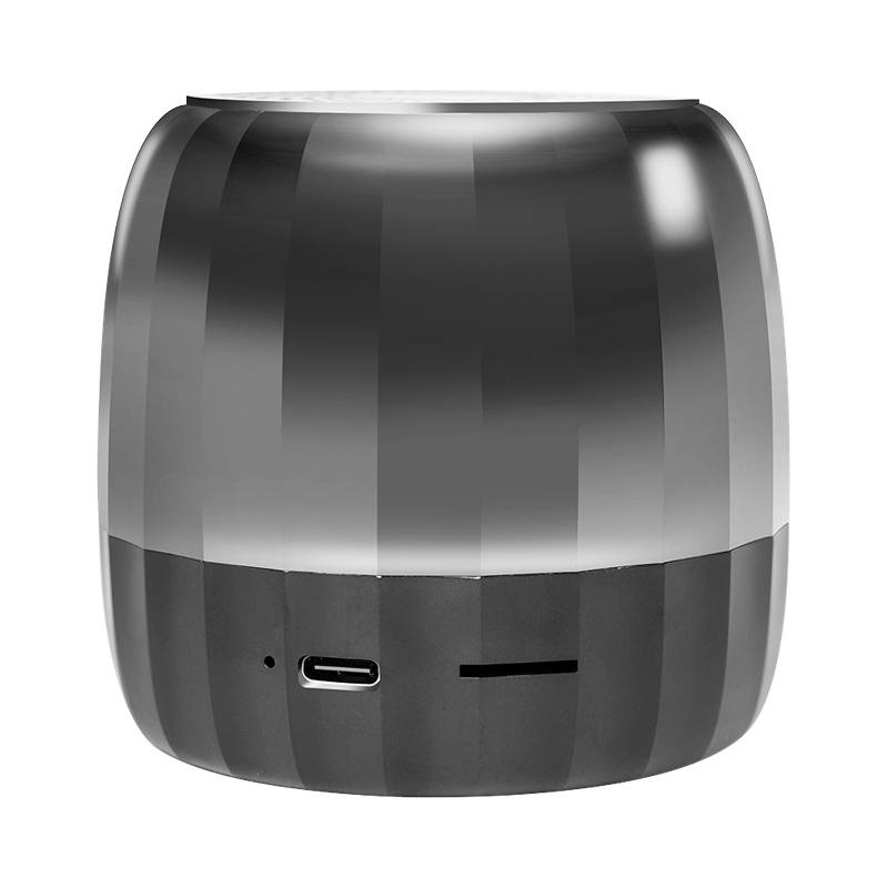 Ein kleiner schwarzer tragbarer Lautsprecher mit einer abgerundeten Würfelform, USB-C-Ladeanschluss an der Vorderseite und schmaler Anzeigeleiste auf weißem Hintergrund.