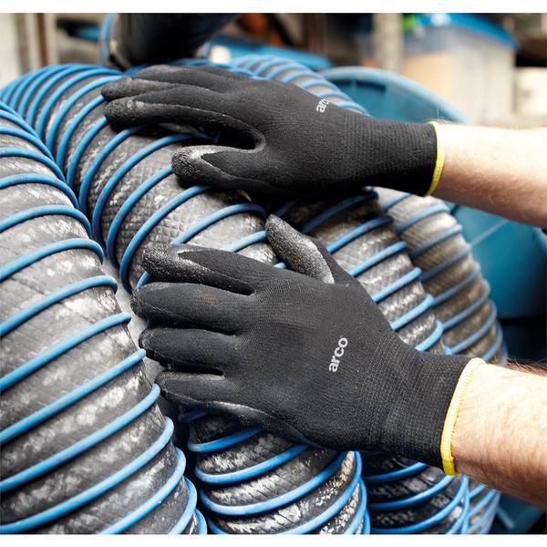 Behandschuhte Hände halten und justieren große aufgerollte industrielle Schläuche oder Leitungsrohre mit blauem Rippenschlauch.