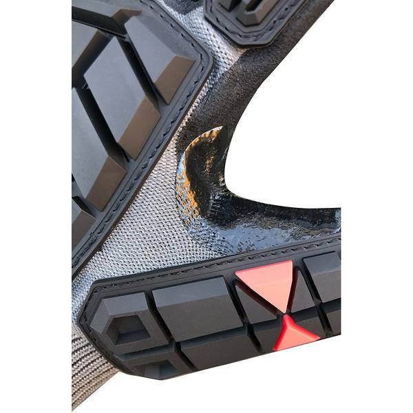 Nahaufnahme einer robusten schwarz-grauen Schuh- oder Stiefellauffläche mit roten Profilen und einem abgenutzten, zerkratzten Fersenbereich.