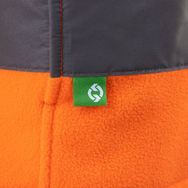 Nahaufnahme einer dunkelgrauen und orangefarbenen Jackennnaht mit einem grünen Gewebelabel, das ein weißes Logo zeigt.