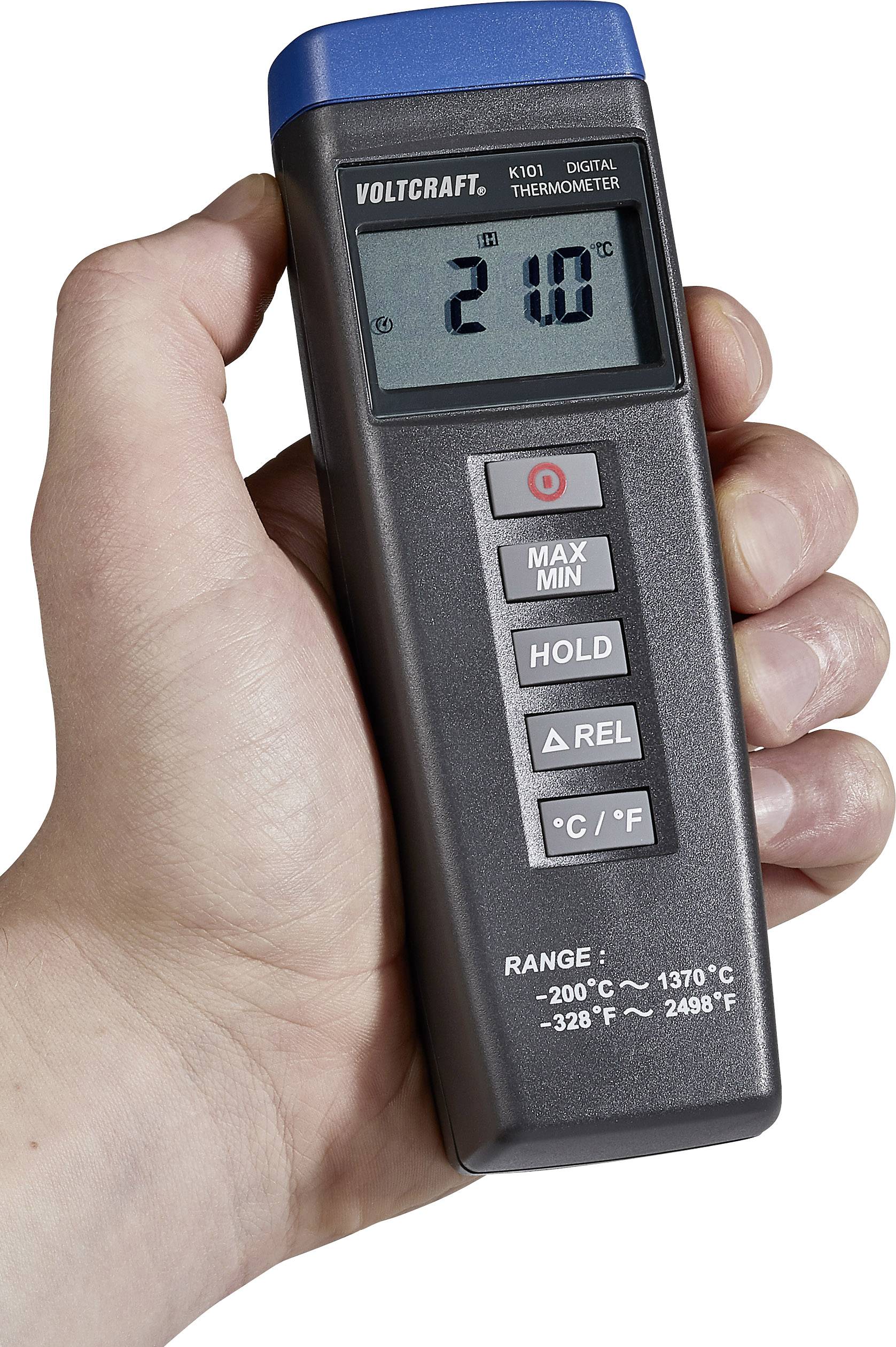 A hand is holding a digital thermometer displaying '21°C'. Beneath it are buttons for various measurement functions.