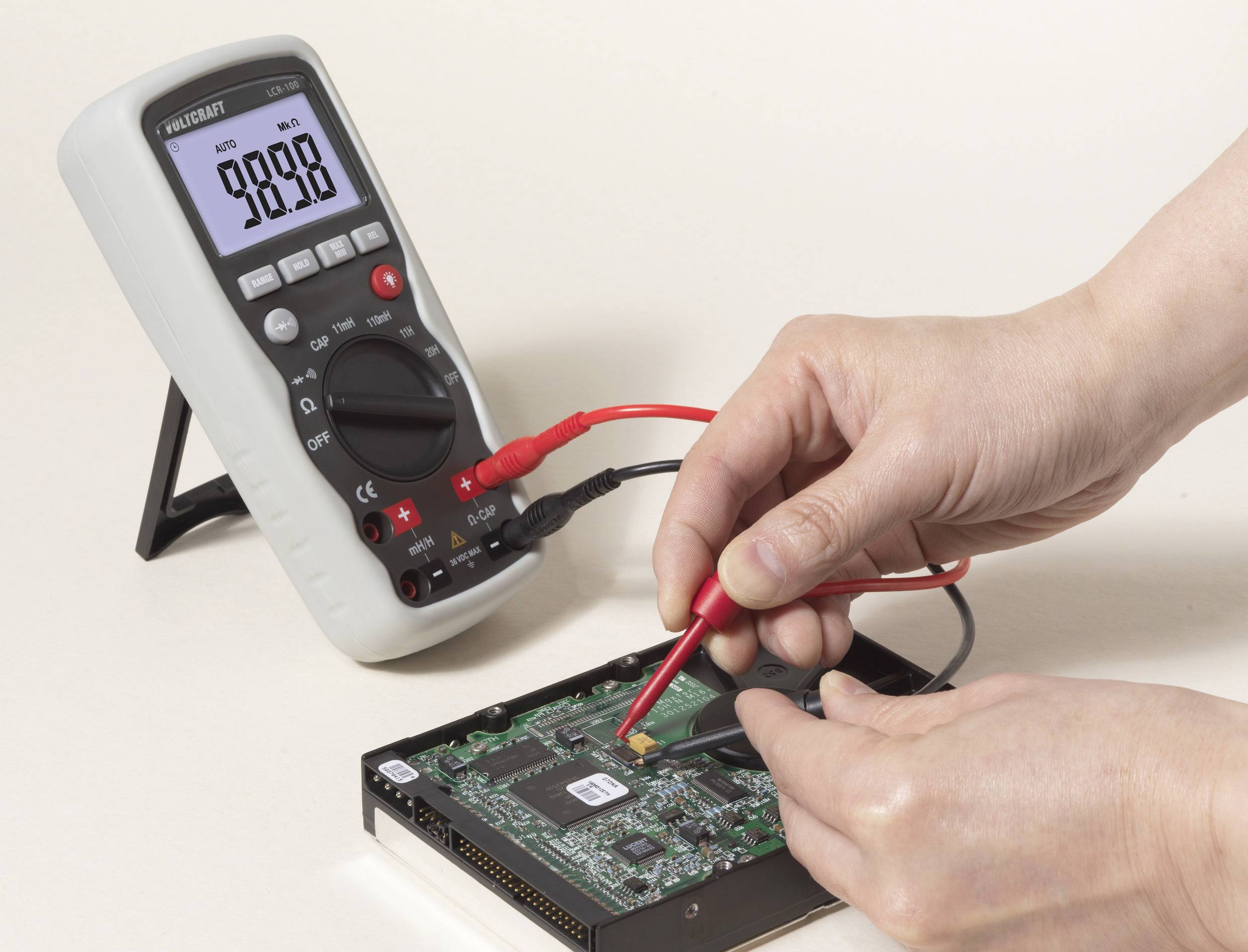 Someone is measuring the voltage on a computer circuit board using a multimeter. The multimeter is displaying 9.888 V.