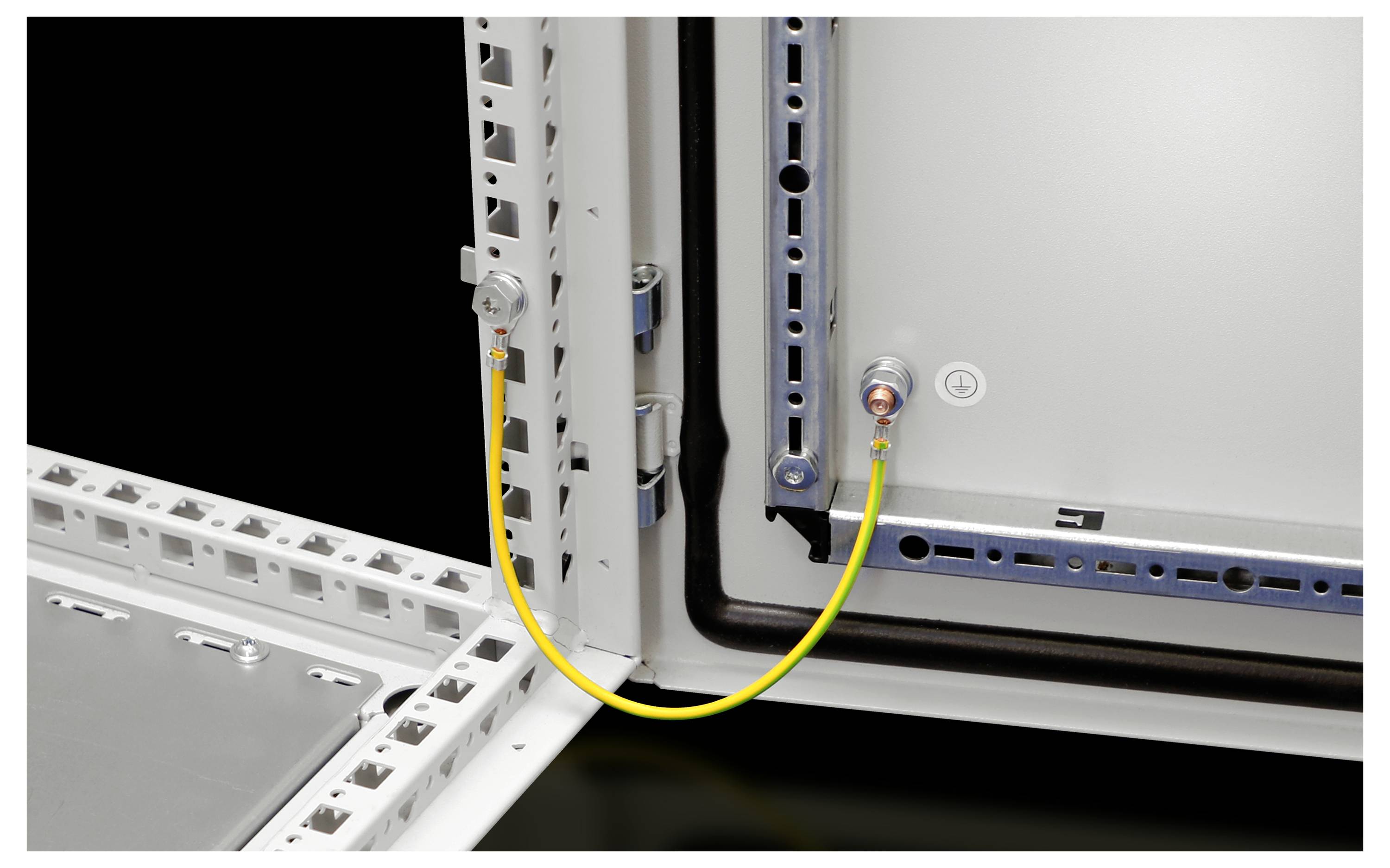 A yellow cable connects two screw terminals in a grey metal frame. It demonstrates a secure earthing in a control cabinet.