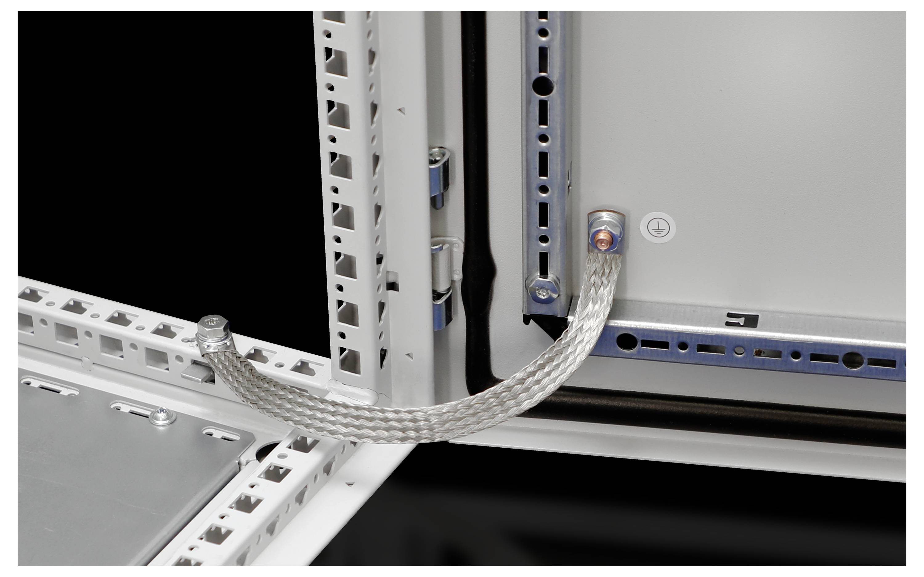 A braided cable connects two metal frames, presumably for earthing in a technical or electrical setup.
