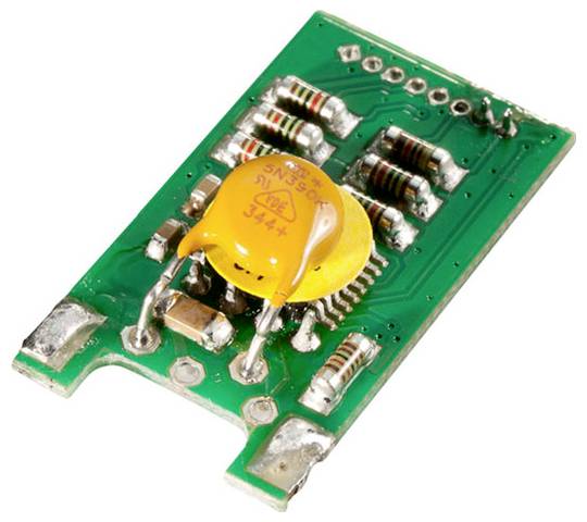 A green circuit board with multiple resistors and a central yellow disc capacitor mounted on it, showing detailed electronic components.