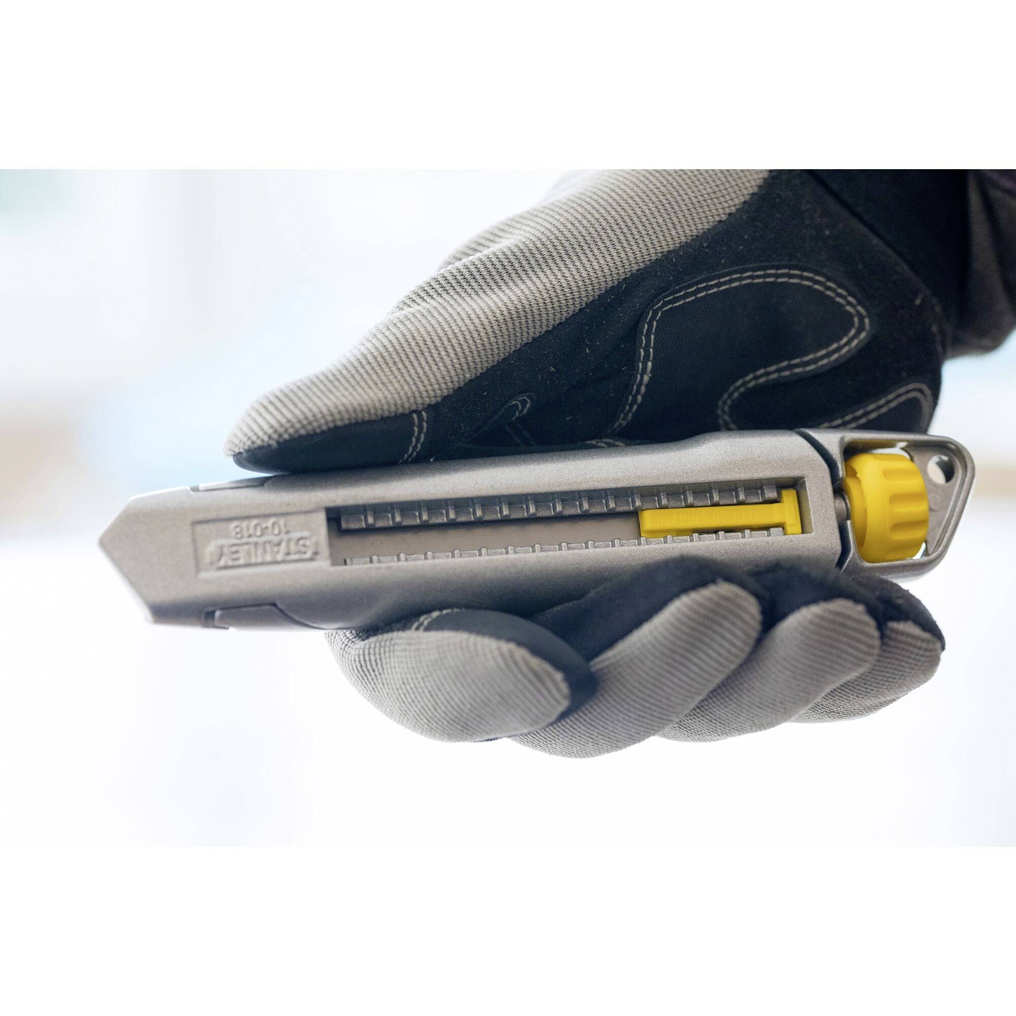 A hand is holding a grey device with a yellow component, resembling a cutting tool. The scale shows various adjustment options.