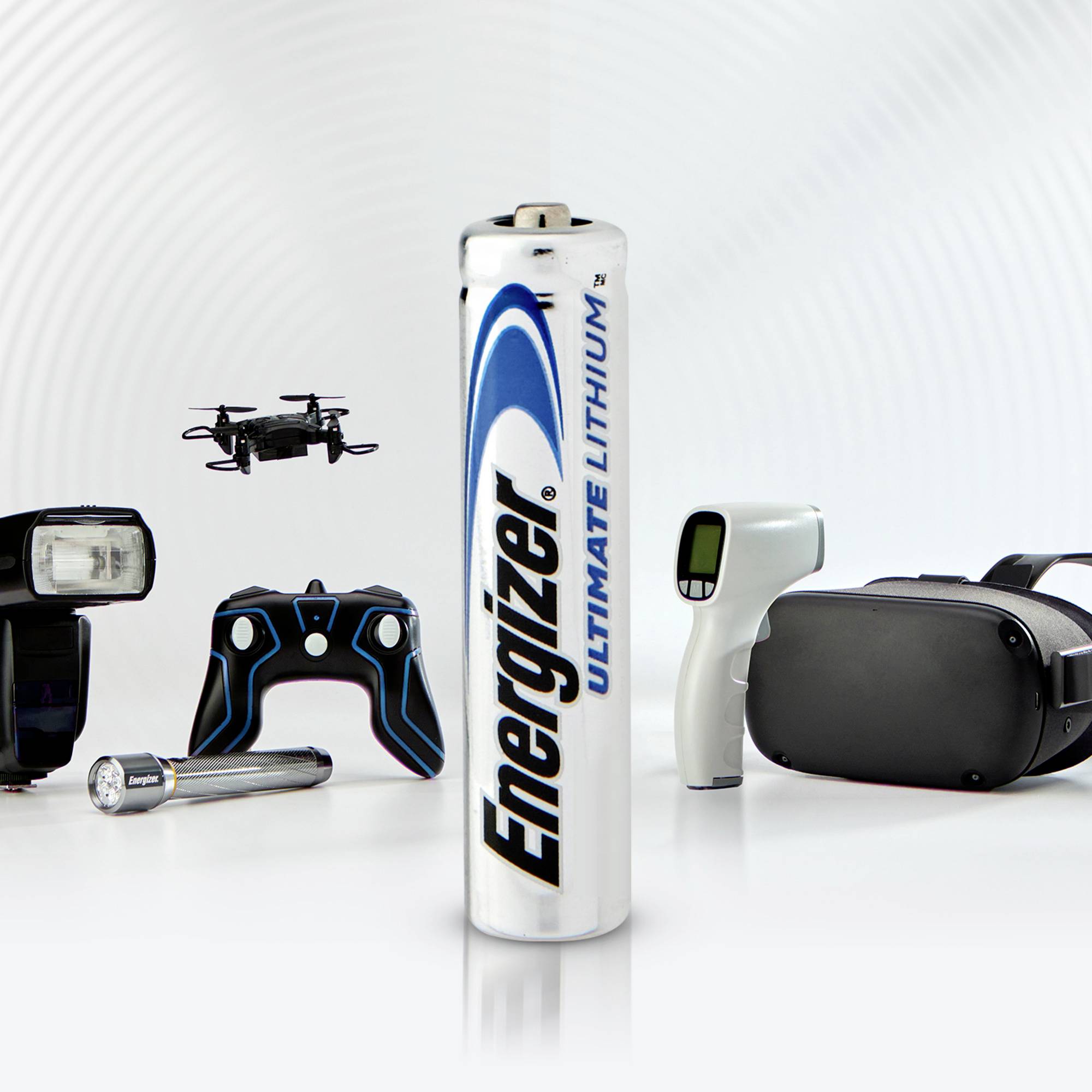 'Energizer Ultimate Lithium Battery' stands upright in the foreground. Technological devices such as a controller and VR headset are visible in the background.