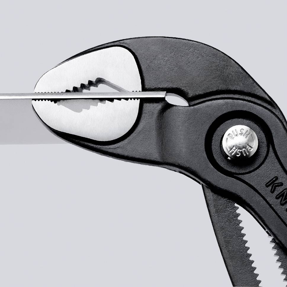 Close-up of a black pair of pliers gripping a thin piece of metal. The pliers have serrated jaws and a push function.