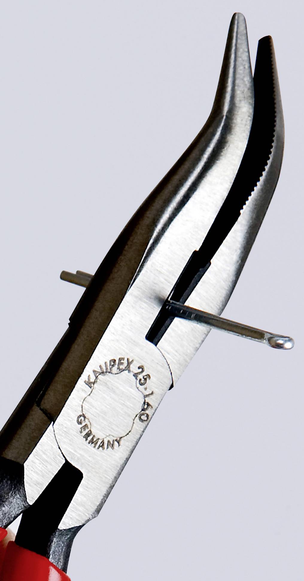 A pair of pliers firmly grips a piece of wire. The pliers are made of metal and have red handles, with a serial number and the inscription 'Germany'.