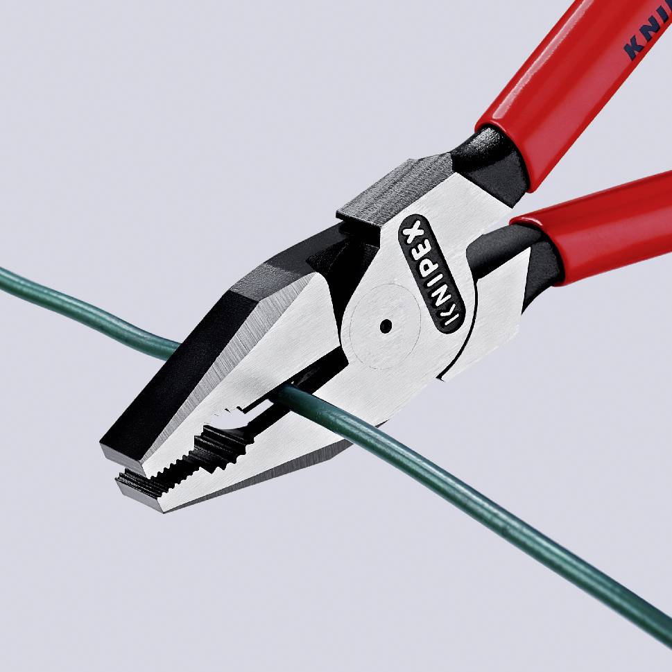 A red pliers cuts a green cable. The pliers have serrated gripping surfaces.