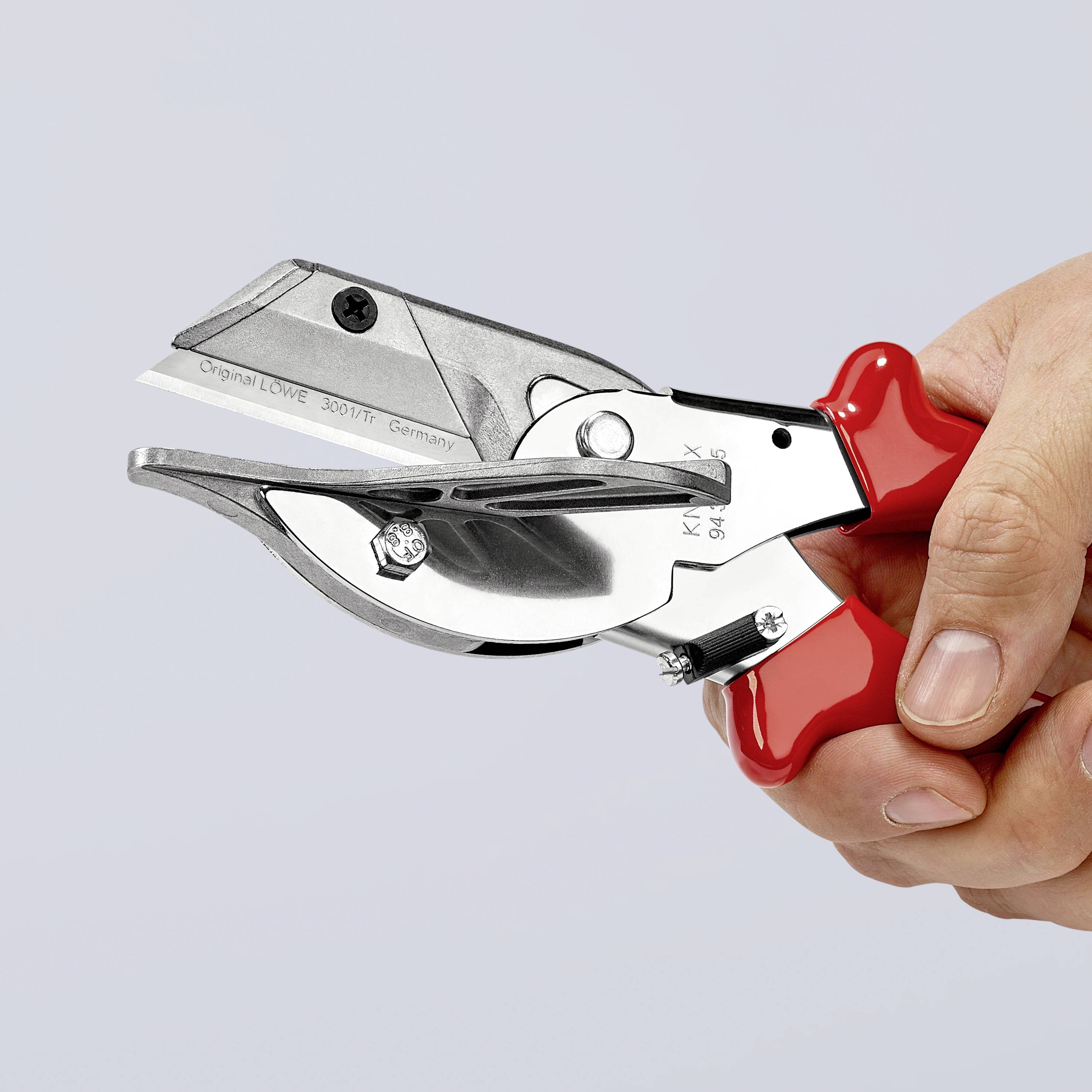 A hand is holding a red metal pruning shears with a curved blade. Designed for precise cutting of branches and twigs.